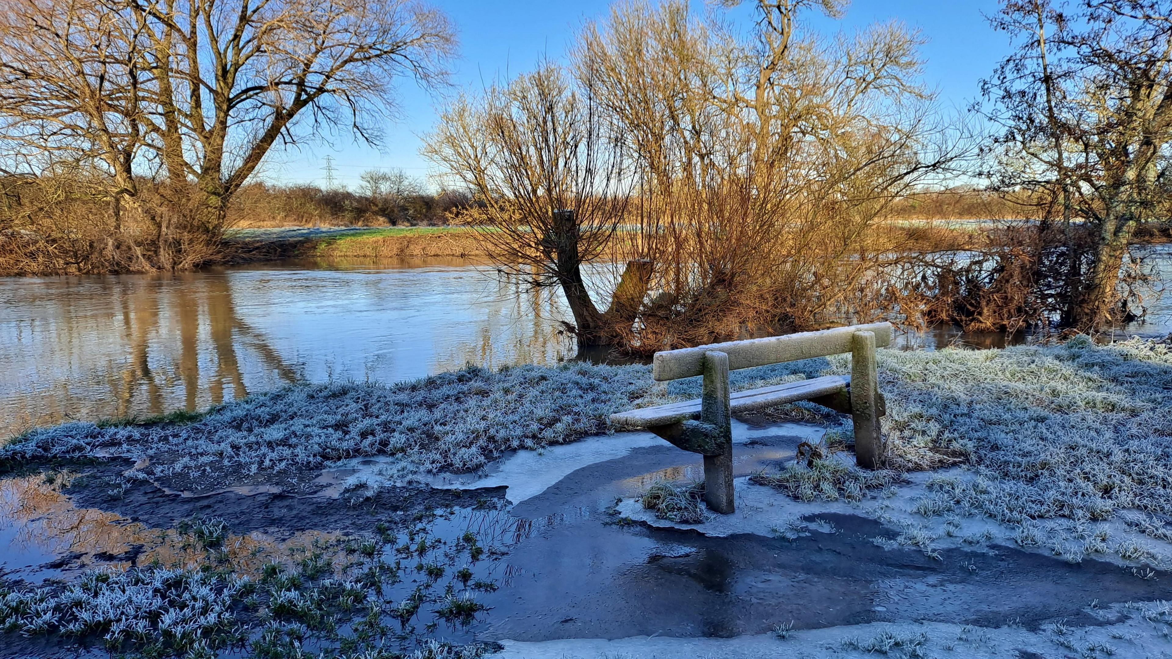 Bench is frozen into river Stour at Kingfisher Barn in Bournemouth

