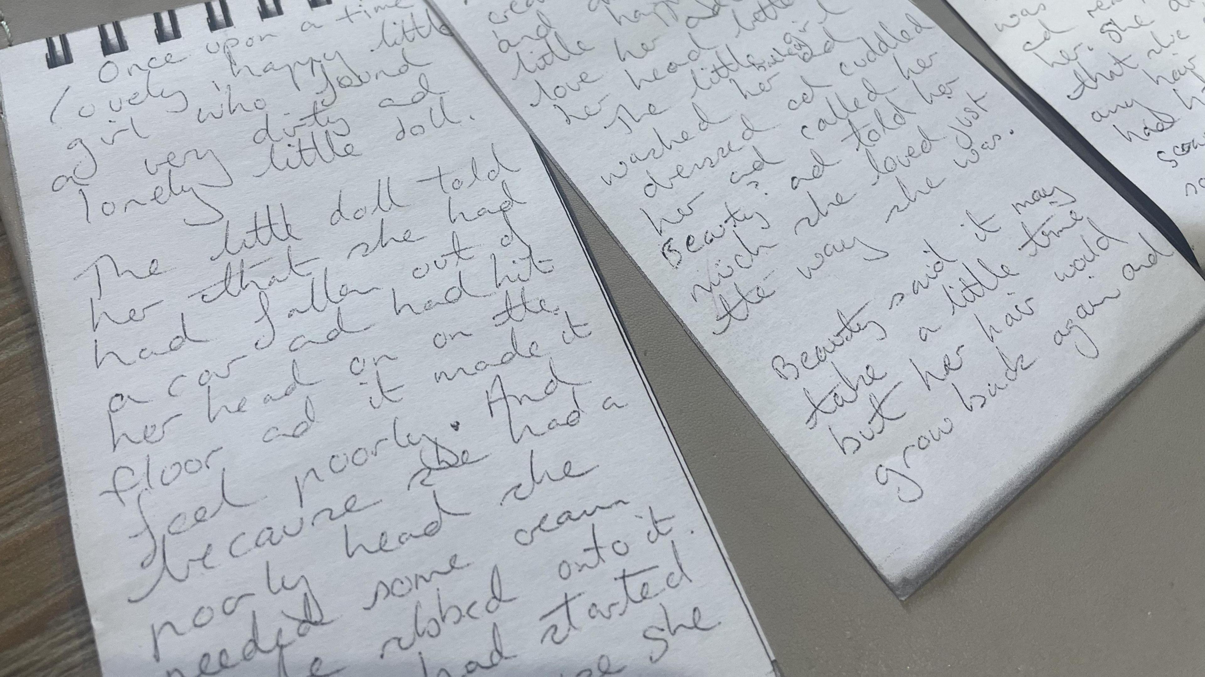 A photograph of three sheets of photocopied notepad sheets with the story of 'The Poorly Doll' written on them.