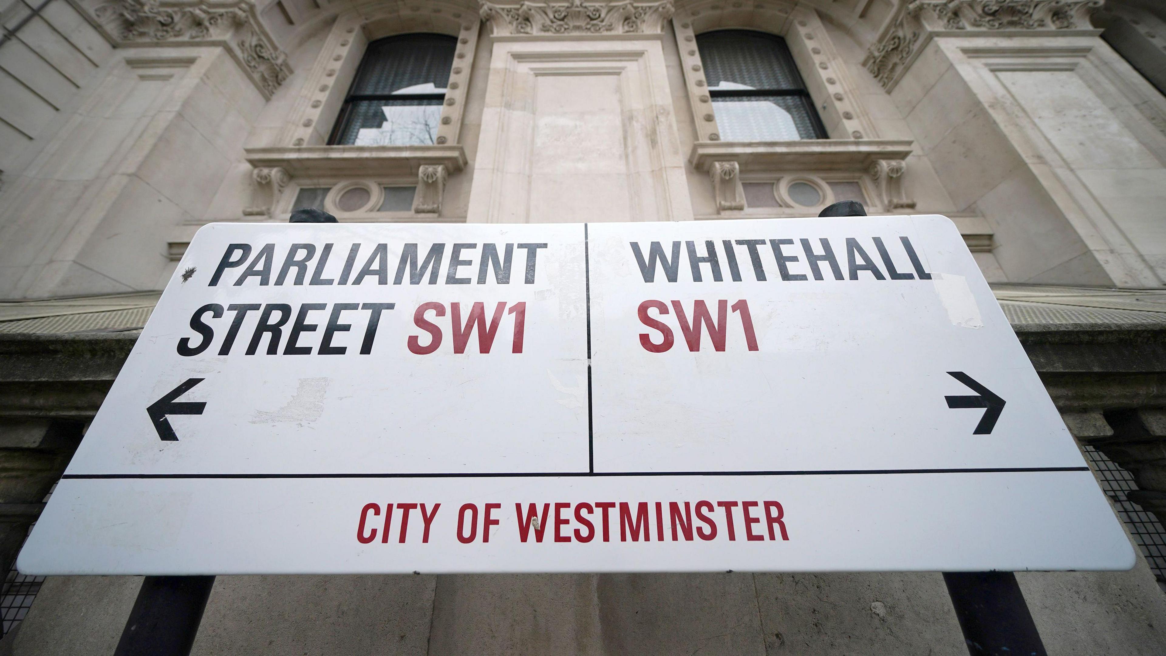 A road sign that points to Parliament Street SW1 to the left and Whitehall SW1 in the City of Westminster