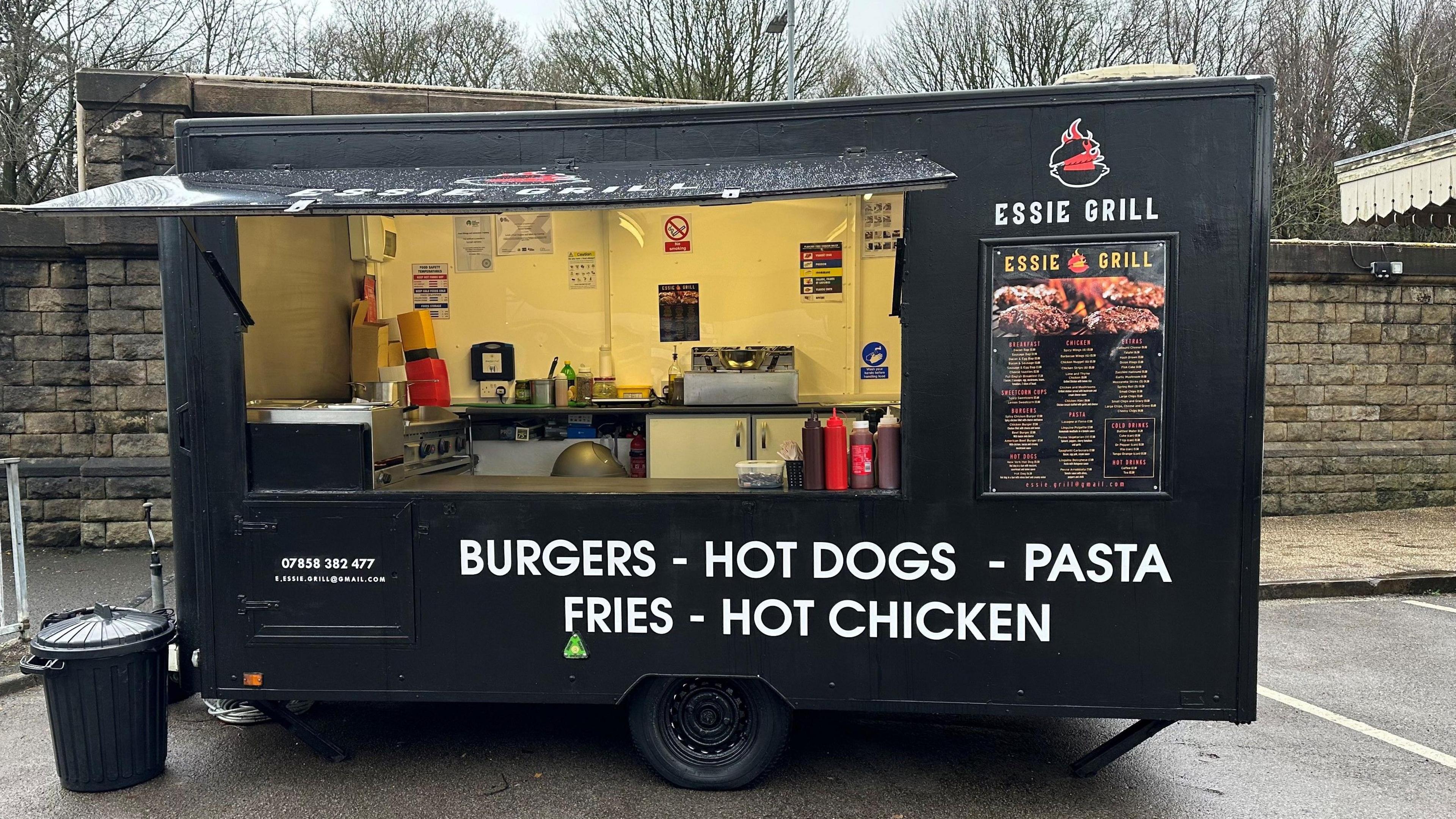 Food trailer in a railway station car park offering burgers, hot dogs and pasta etc