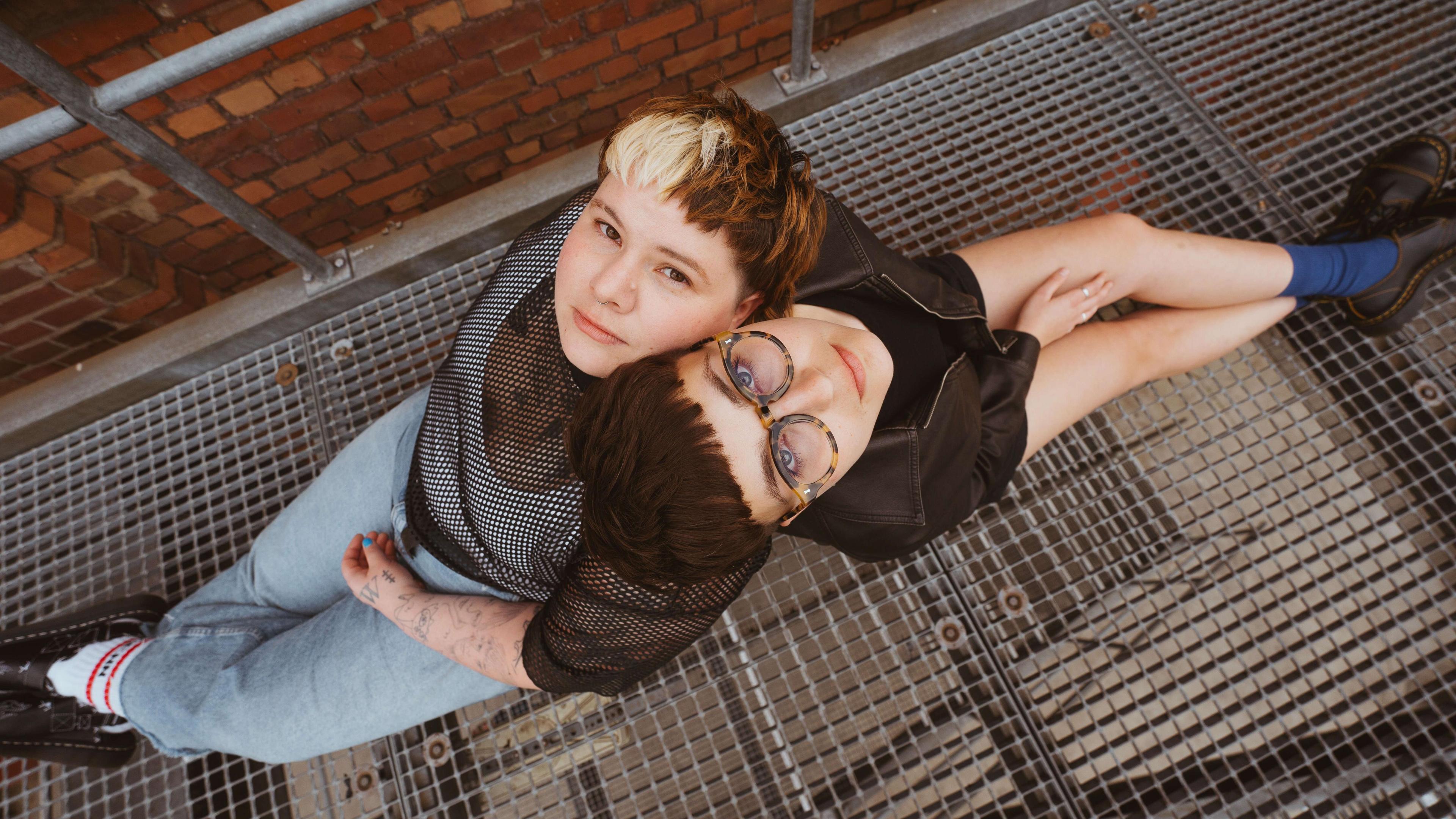 Hanni Pidduck and Clara Townsend sitting on a metal walkway looking up at the camera