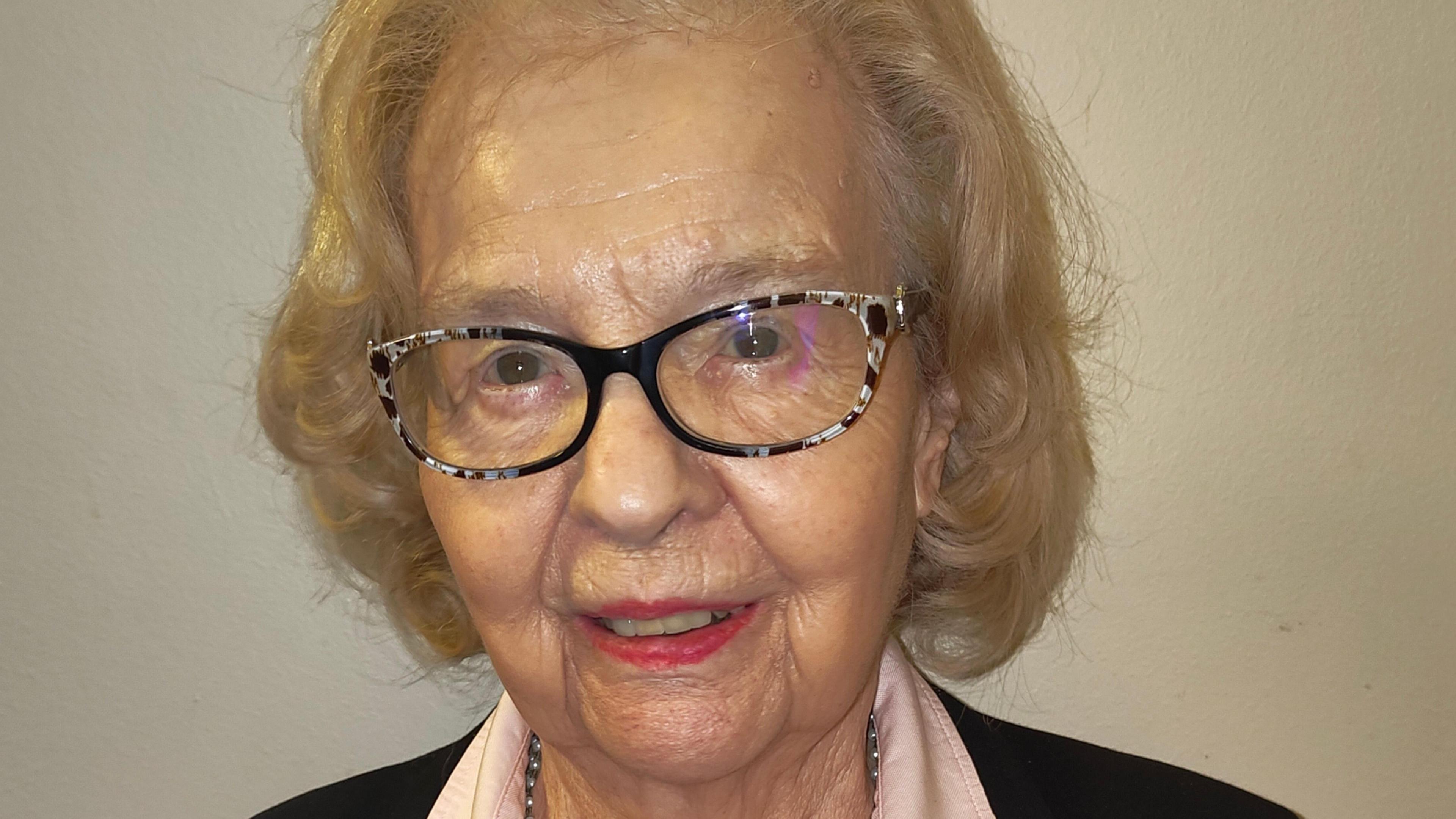 Baroness Liln Golding who has short blonde hair and dark rimmed glasses, smiles at the camera.