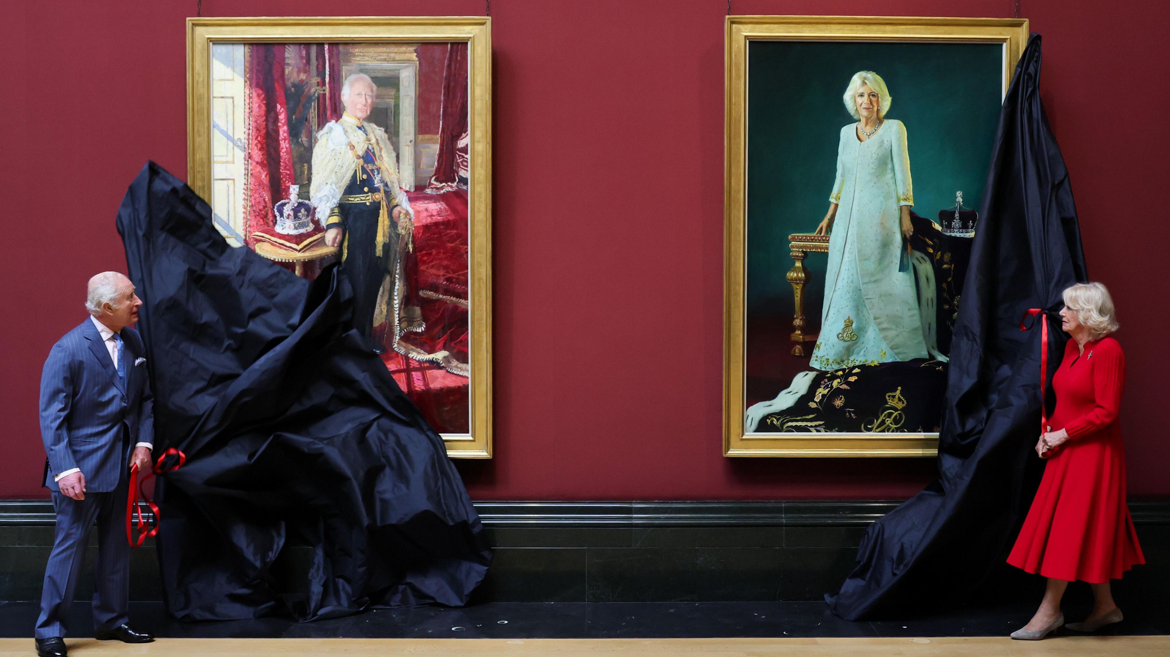 King Charles and Queen Camilla removing covers from portraits depicting them