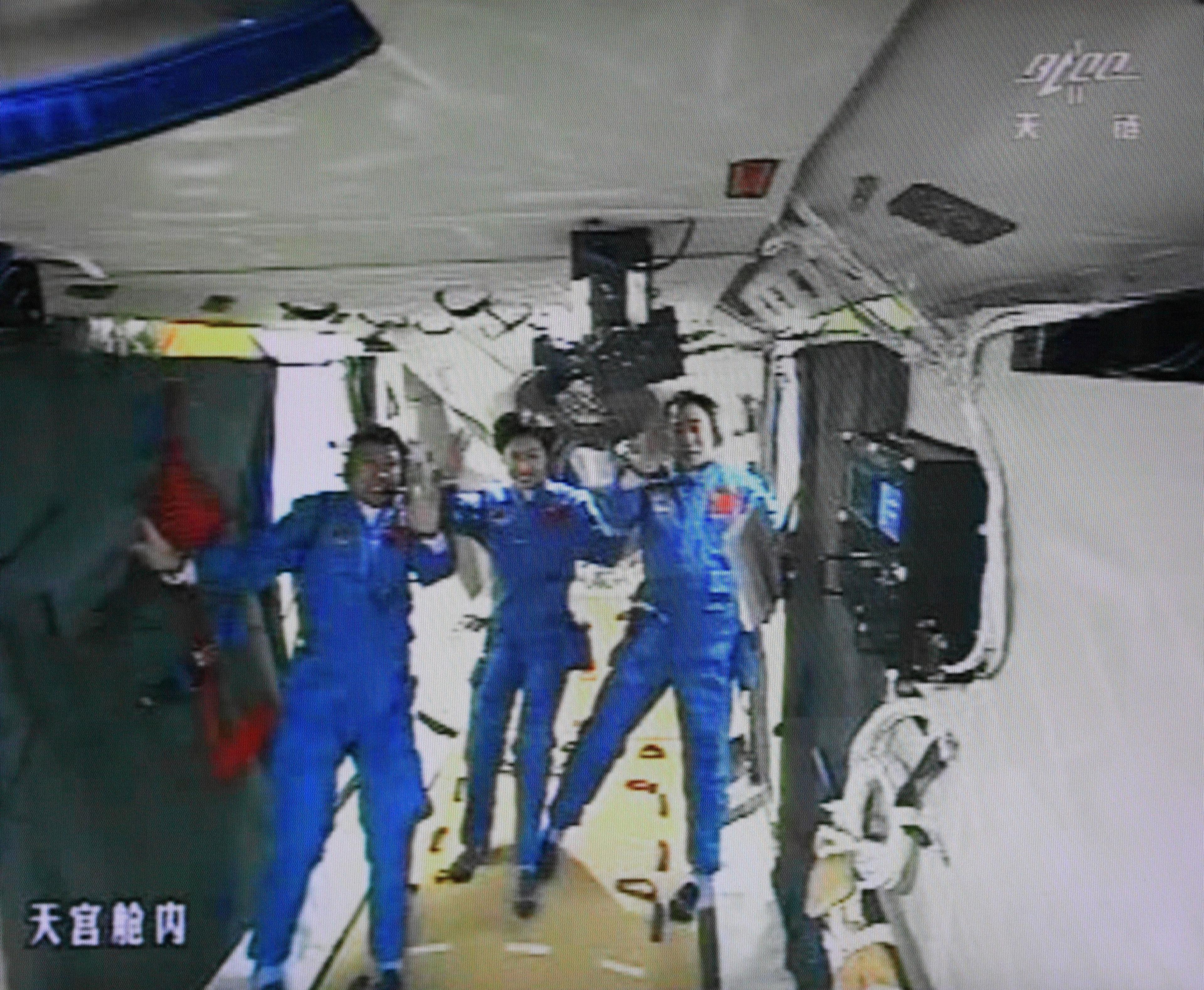 This photo of the giant screen at the Jiuquan space center shows three Chinese astronauts (from left) Liu Wang, the first Chinese woman in space, Jing Haipeng and Liu Yang in the Tiangong-1 lab on June 18, 2012.