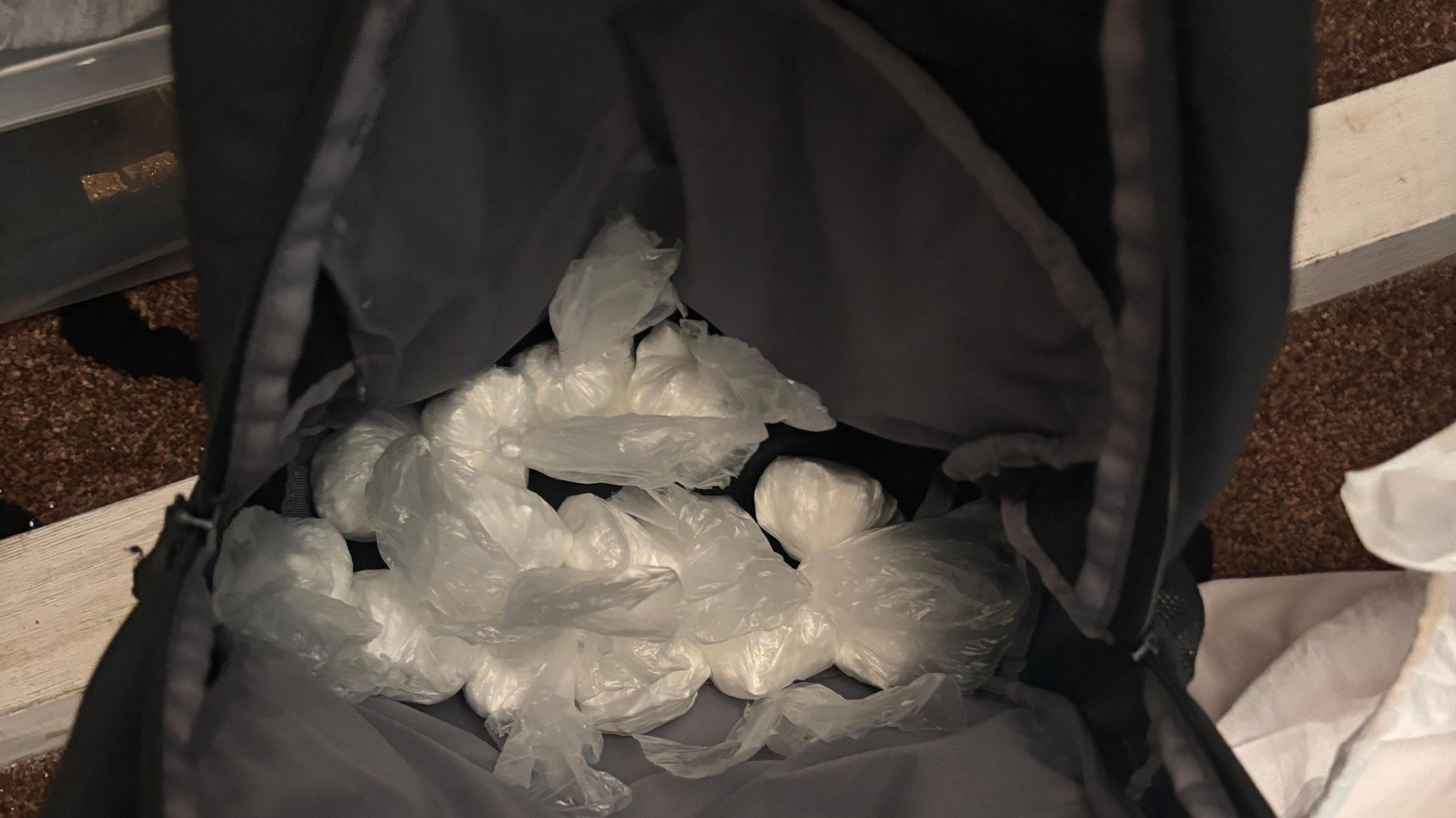 Small white bags of cocaine inside a black bag.
