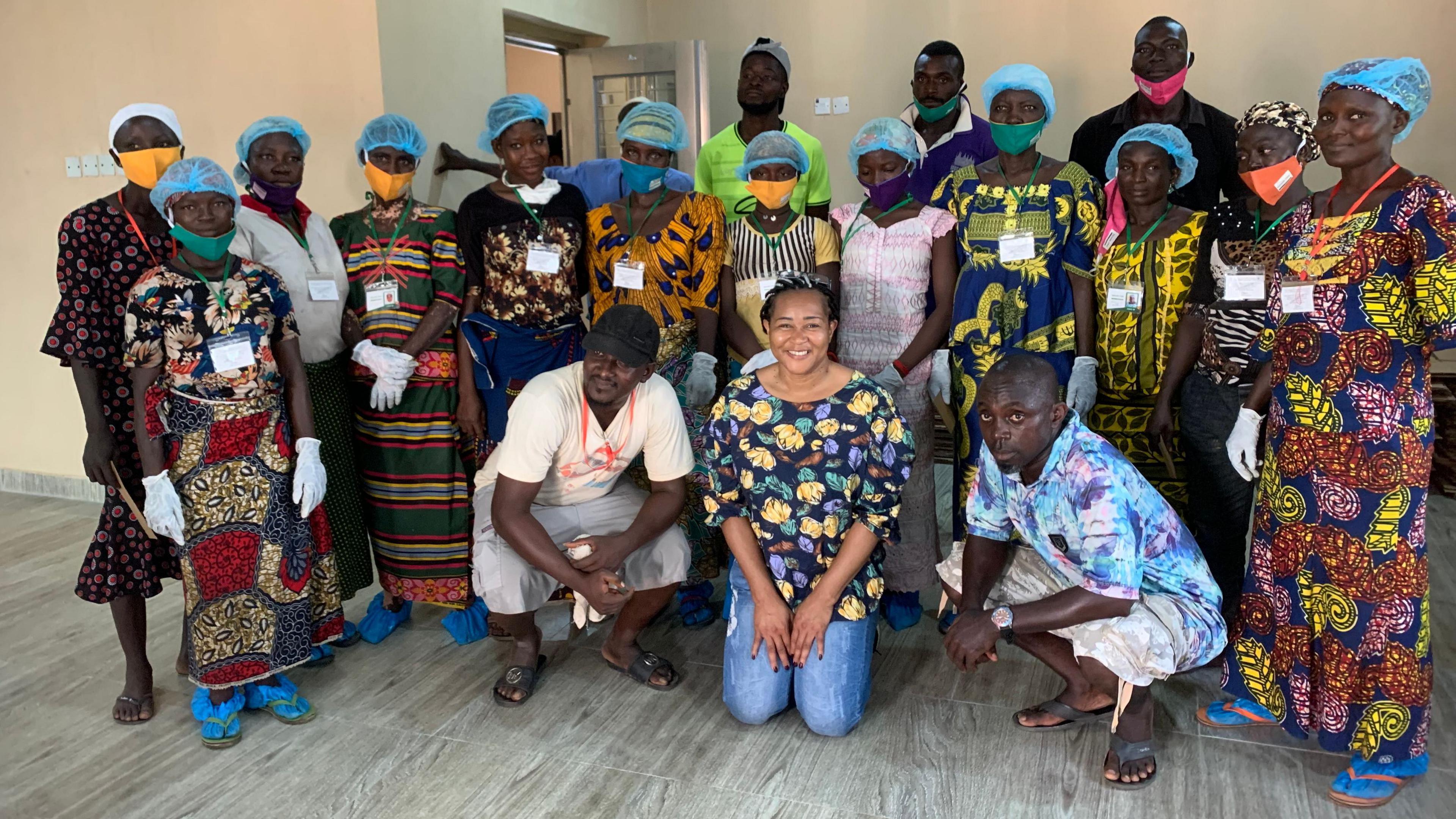 A group of men and women, wearing facemasks, and hair nets, looking at the camera 