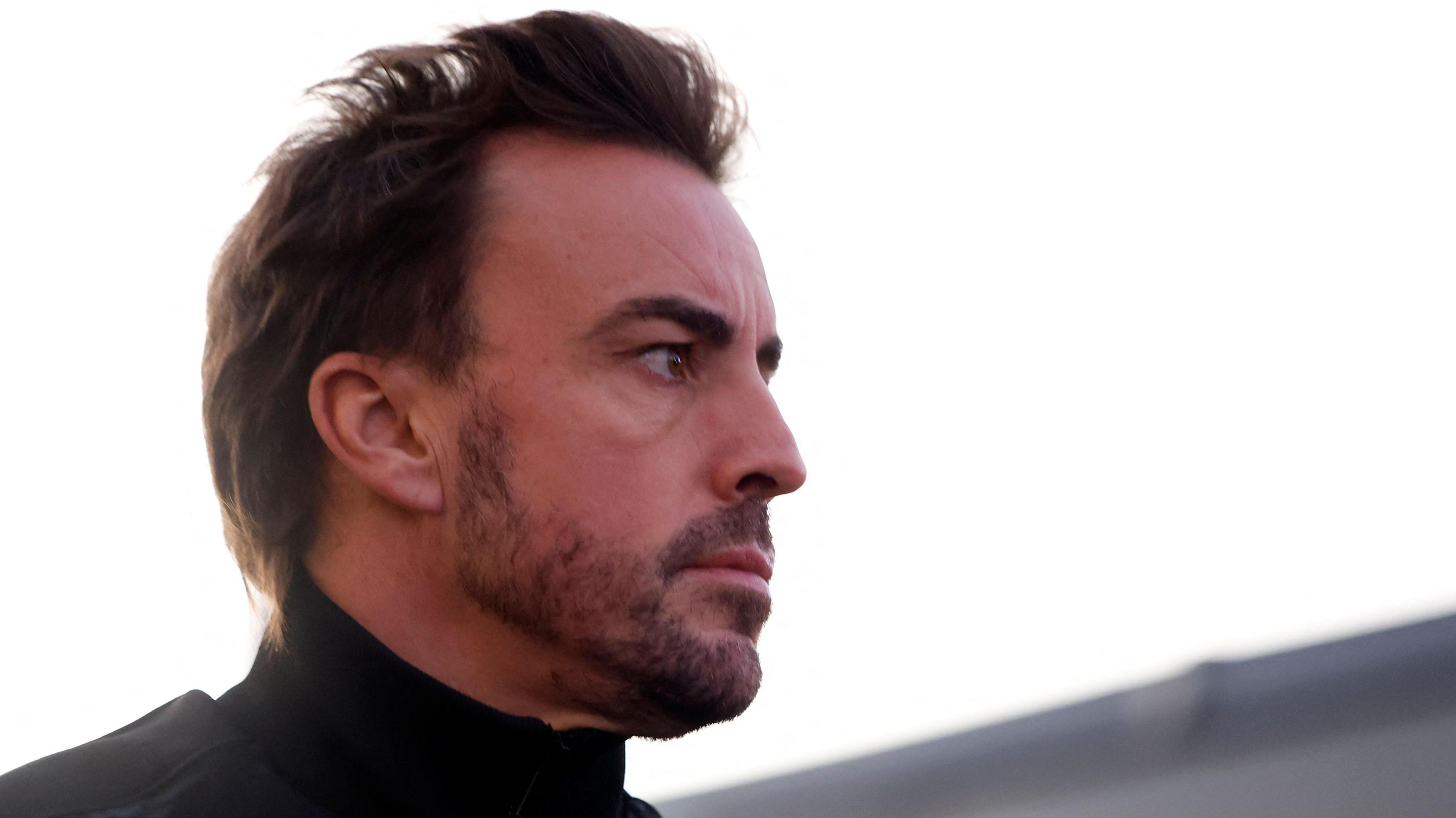 Fernando Alonso pictured staring to the right while wearing a black roll-neck top