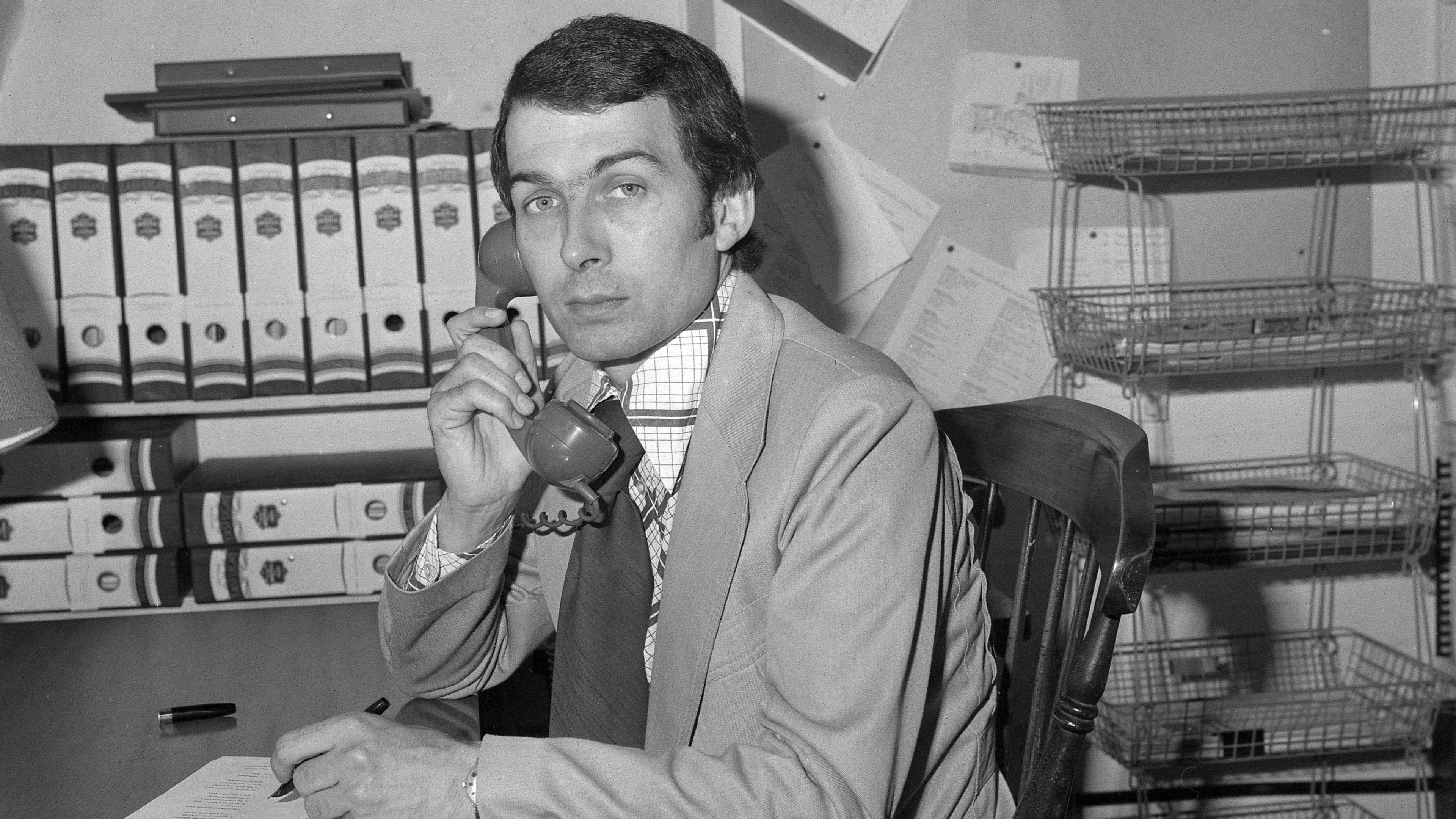 Frank Field in his London office in 1976 on the phone and holding a fountain pen