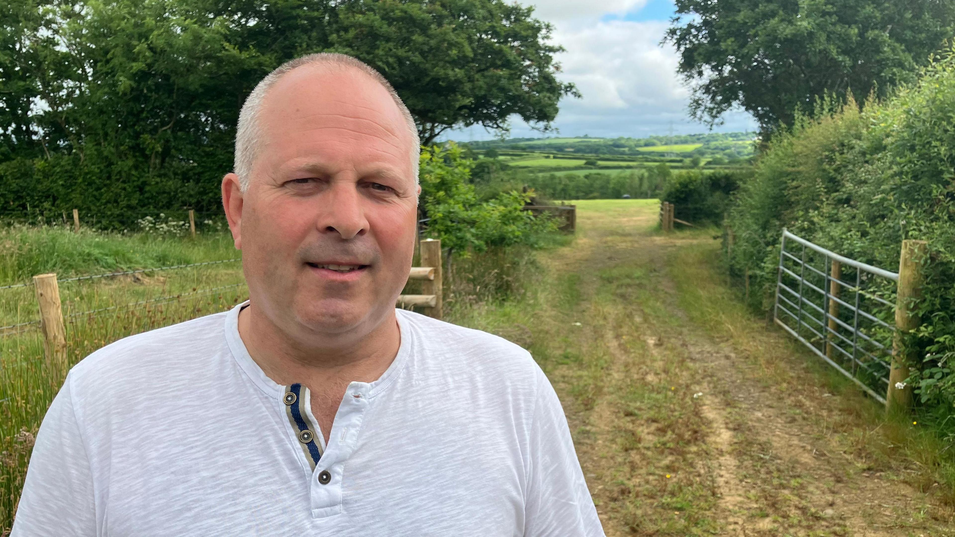 Man standing on a track in the countryside with fields in the background