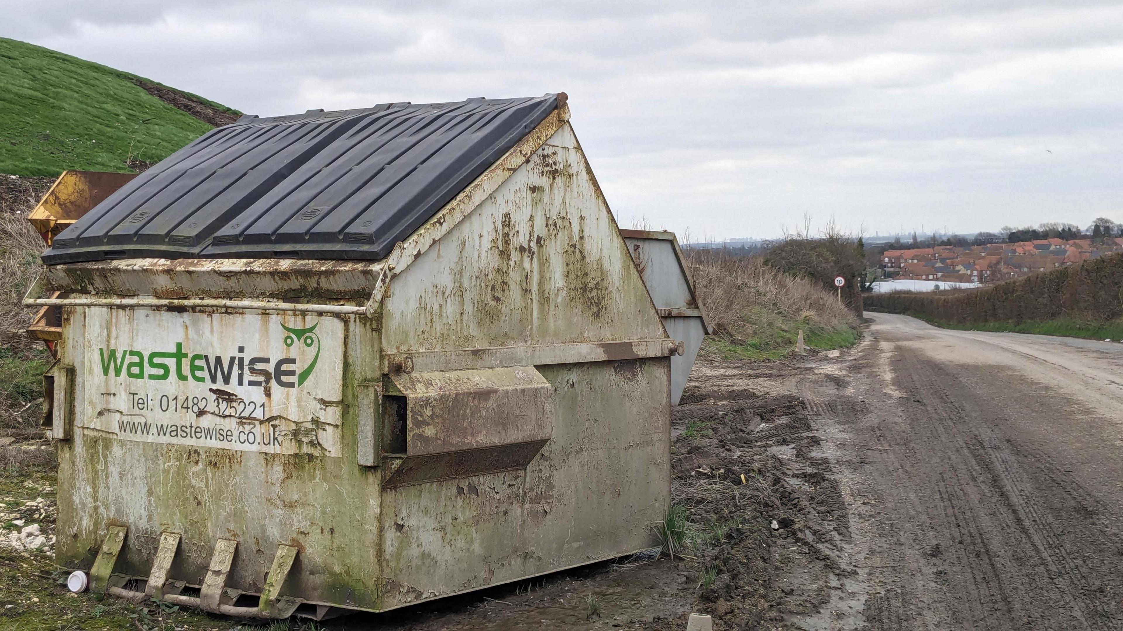 A skip with houses in the distance.