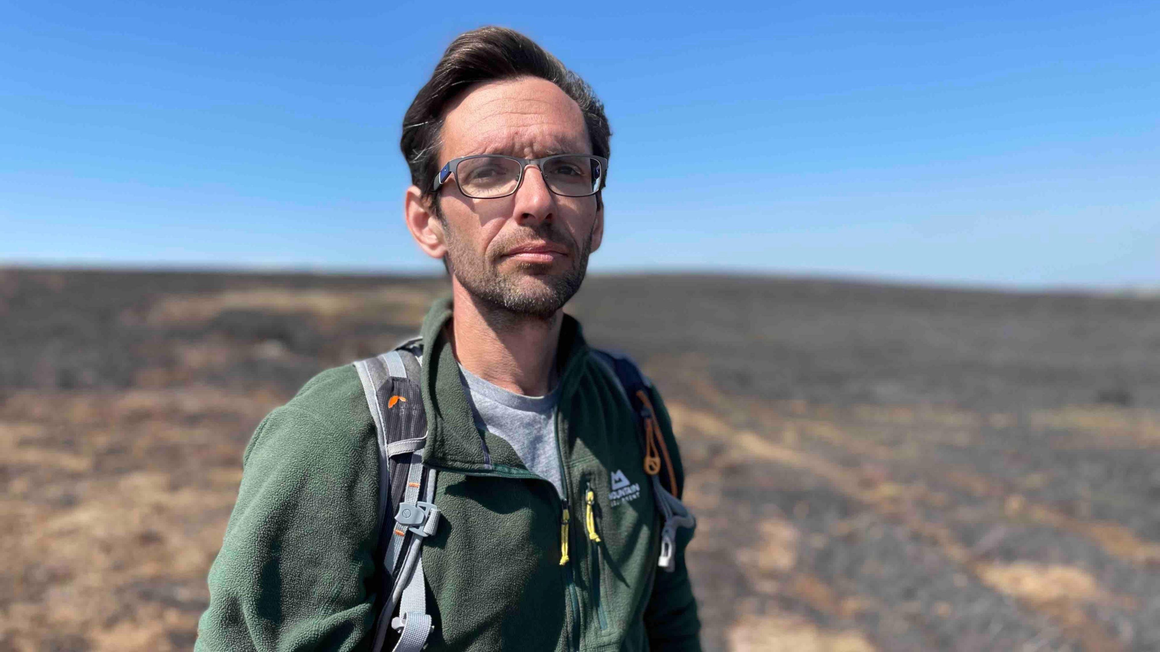 Jim Randle from the 'Moors for the Future' partnership is pictured wearing a green jumper on moorland where there was a major fire