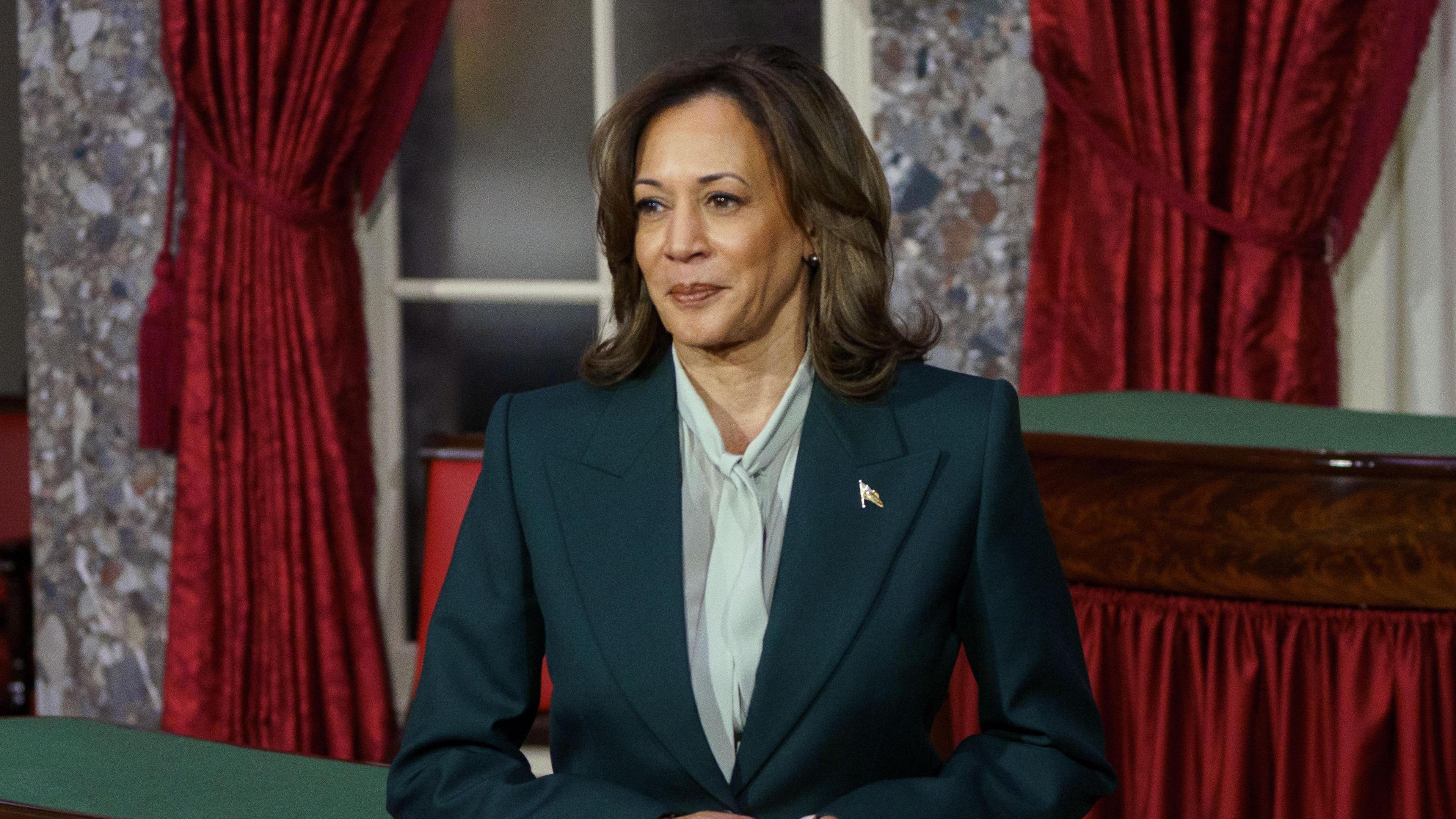 A woman in a green suit and blouse stands in the Old Senate Chamber at the US Capitol, Washington