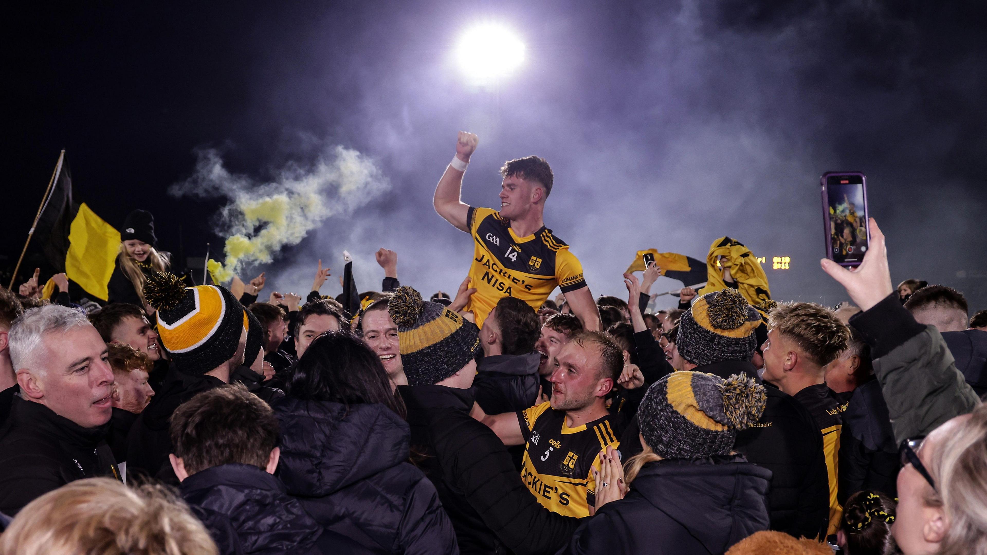 Ruairi McCullagh celebrates winning the Tyrone title with fans on the Healy Park pitch.