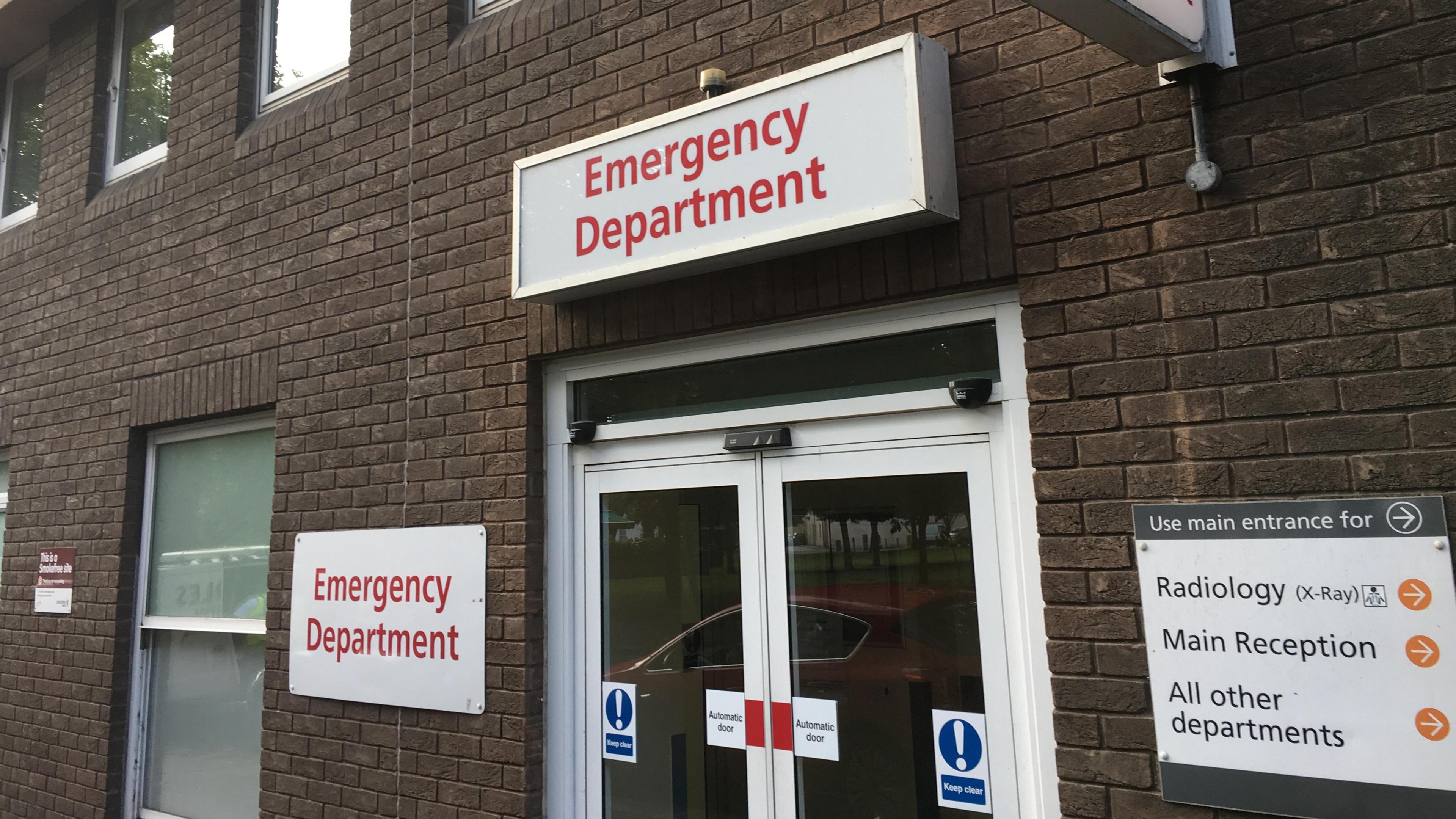 Close picture of Jersey's Accident and Emergency department. A brick building with a white door. 