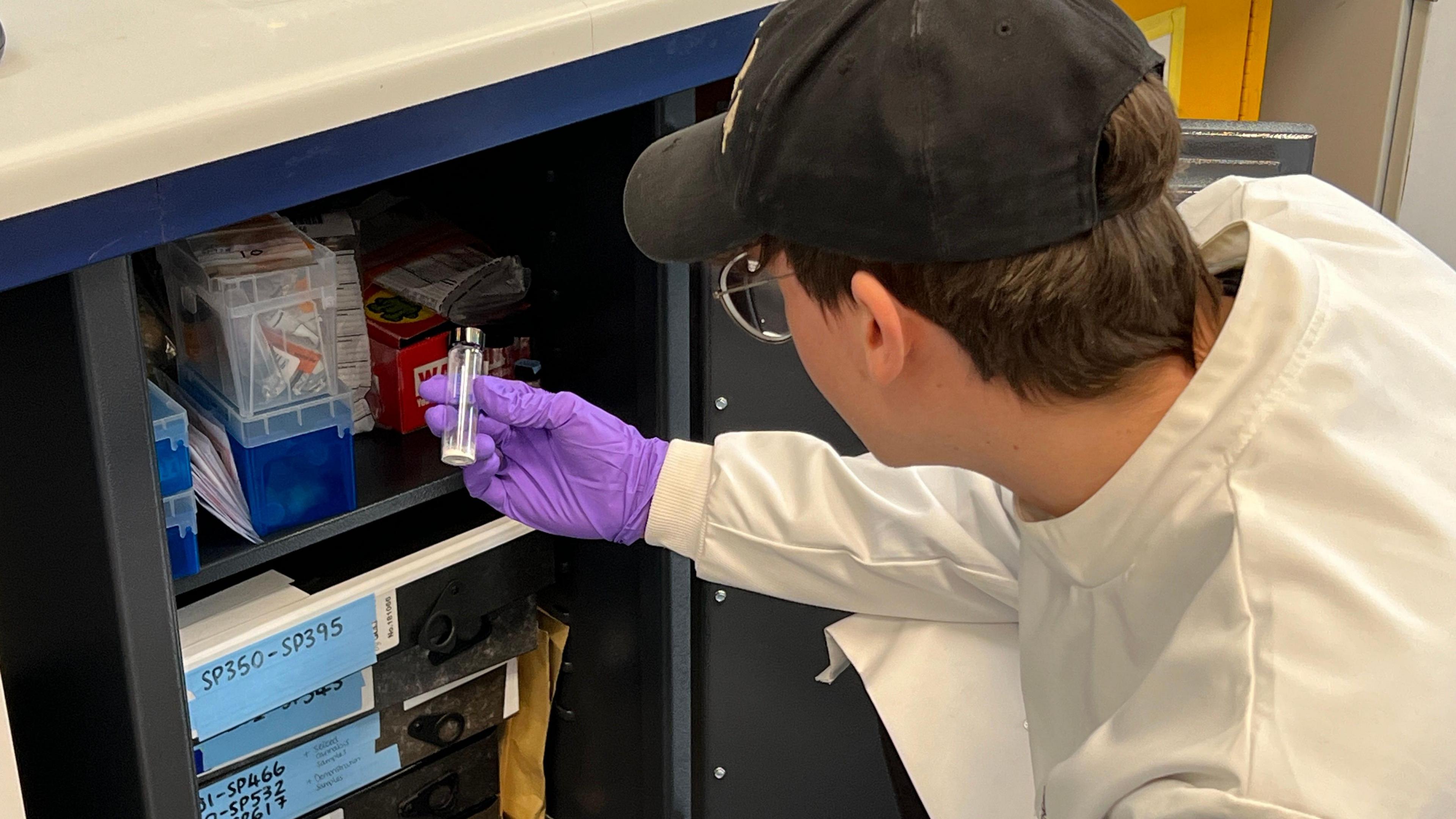 A student picking up a valve from a cupboard