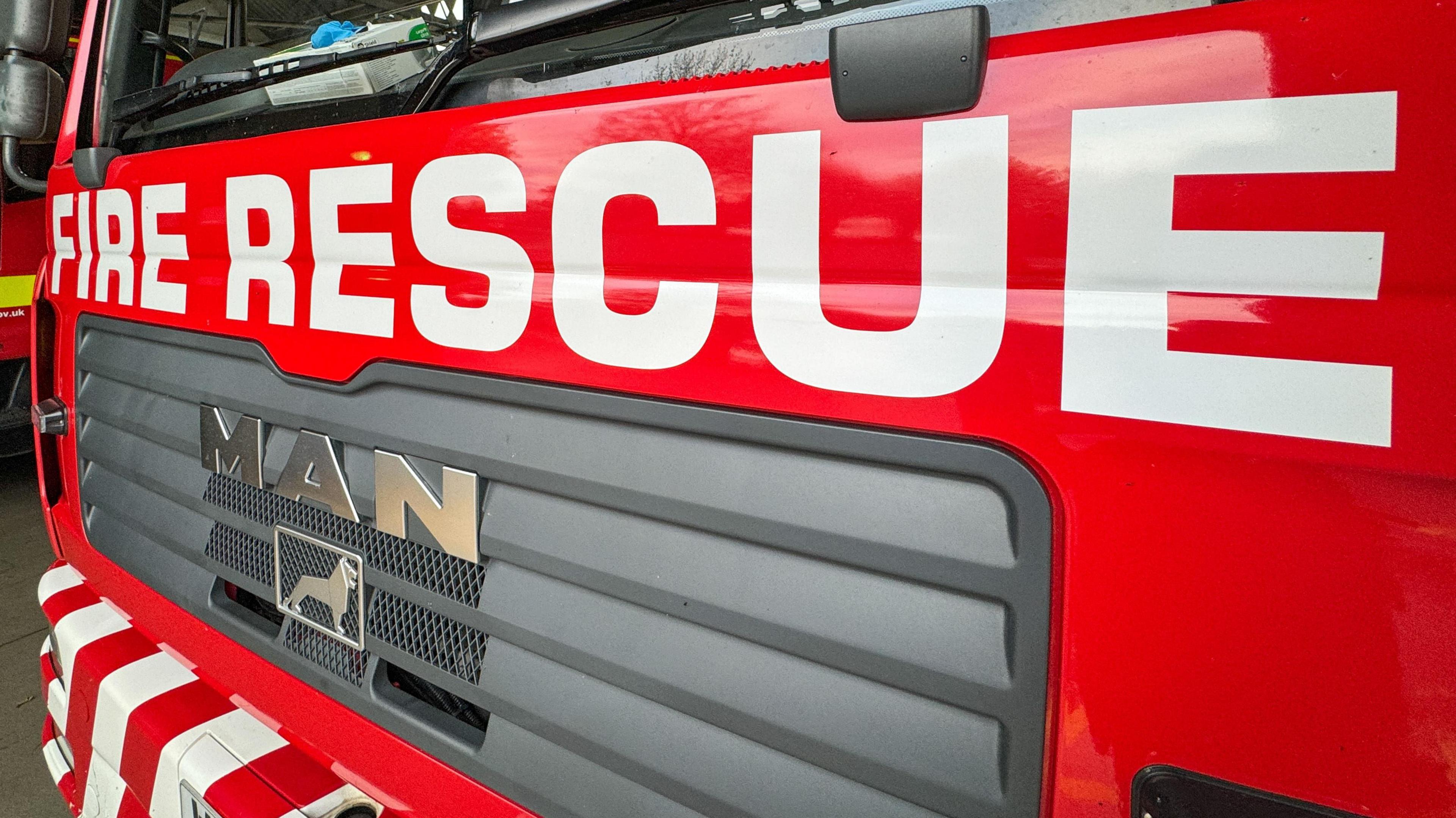 A close-up of the front of a fire engine with the words FIRE RESCUE in white text on the front.