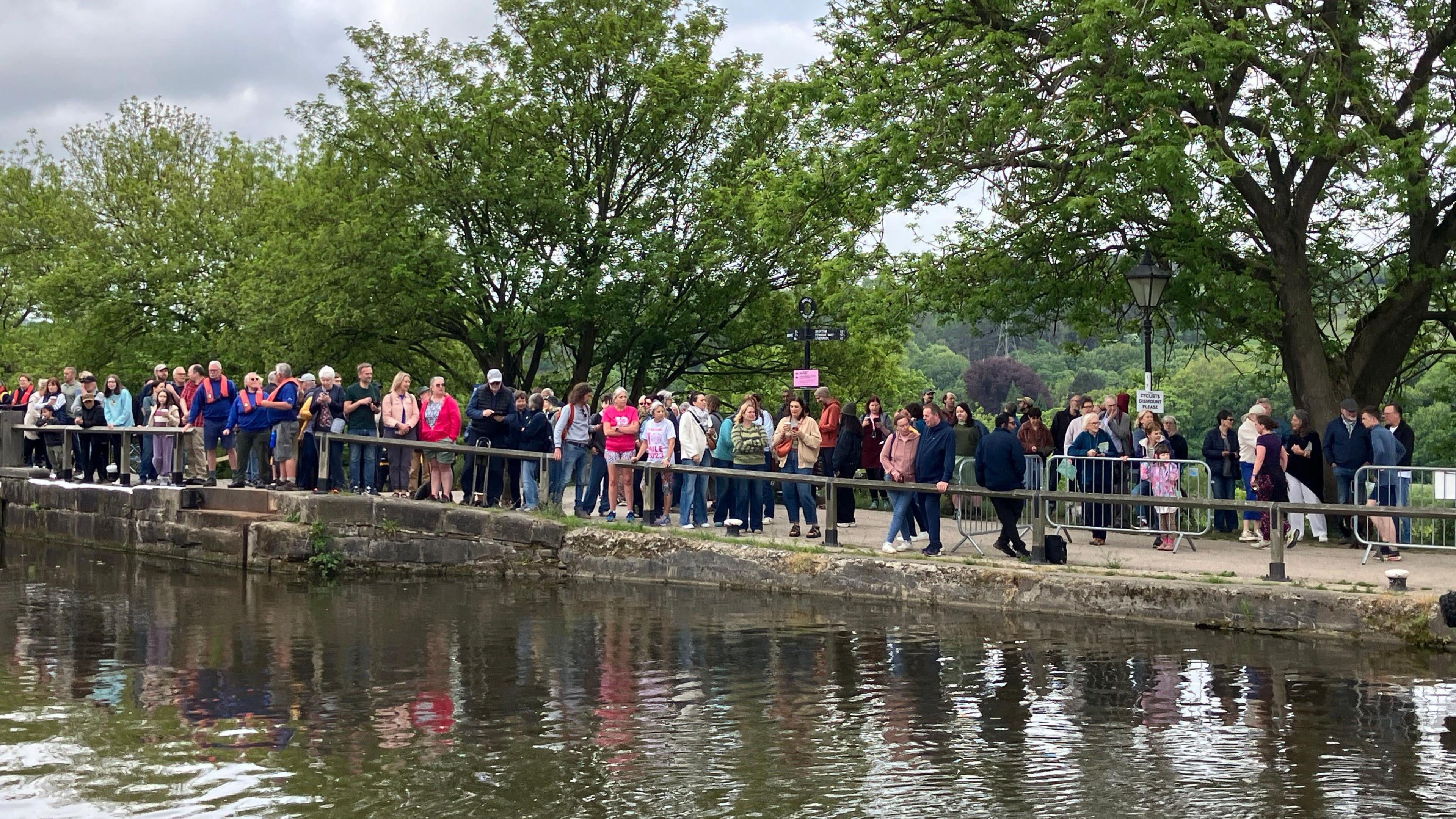 Crowds of people stand on the canalside