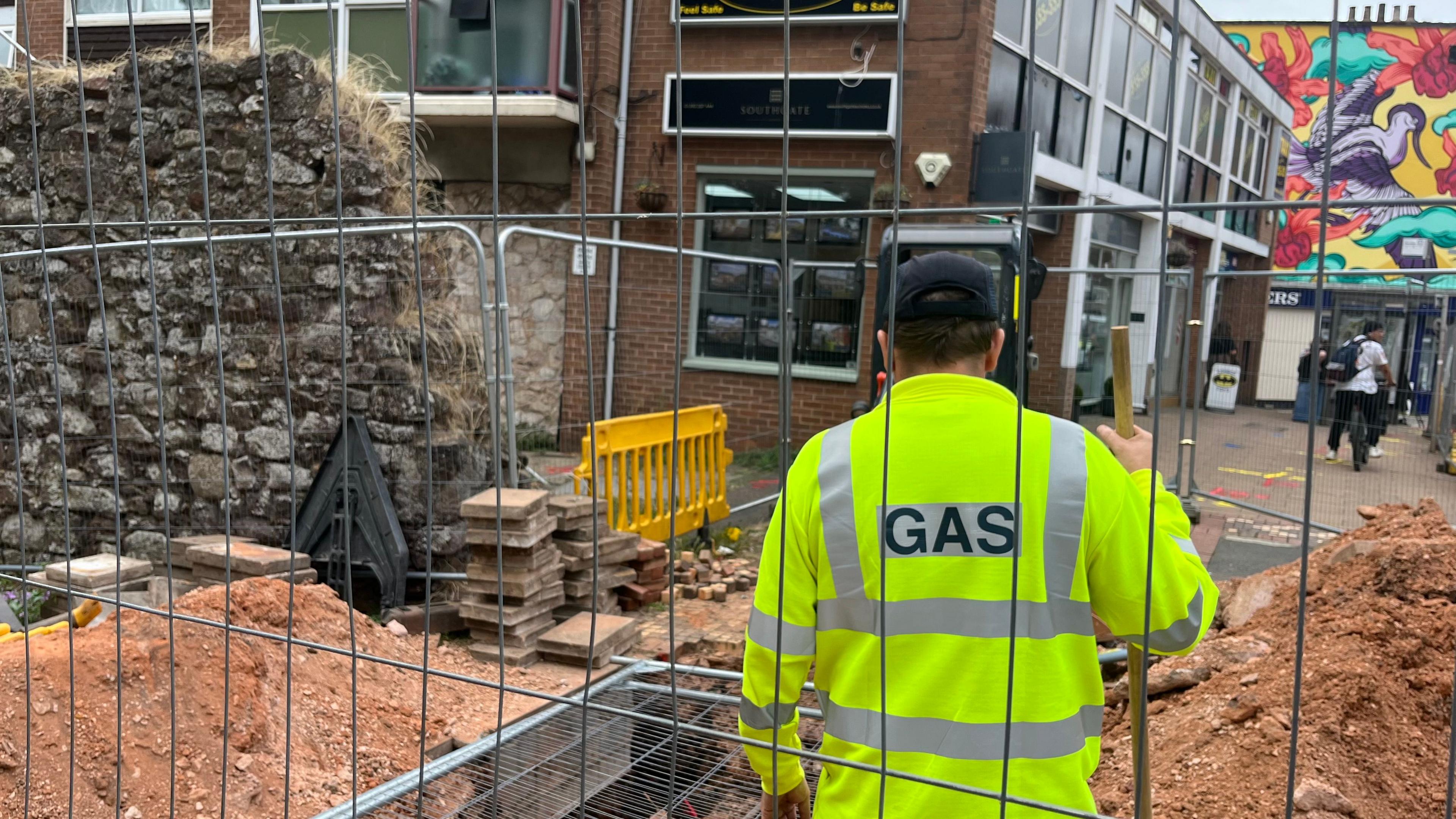 A Wales and West worker standing near the hole dug up by Exeter's Roman wall