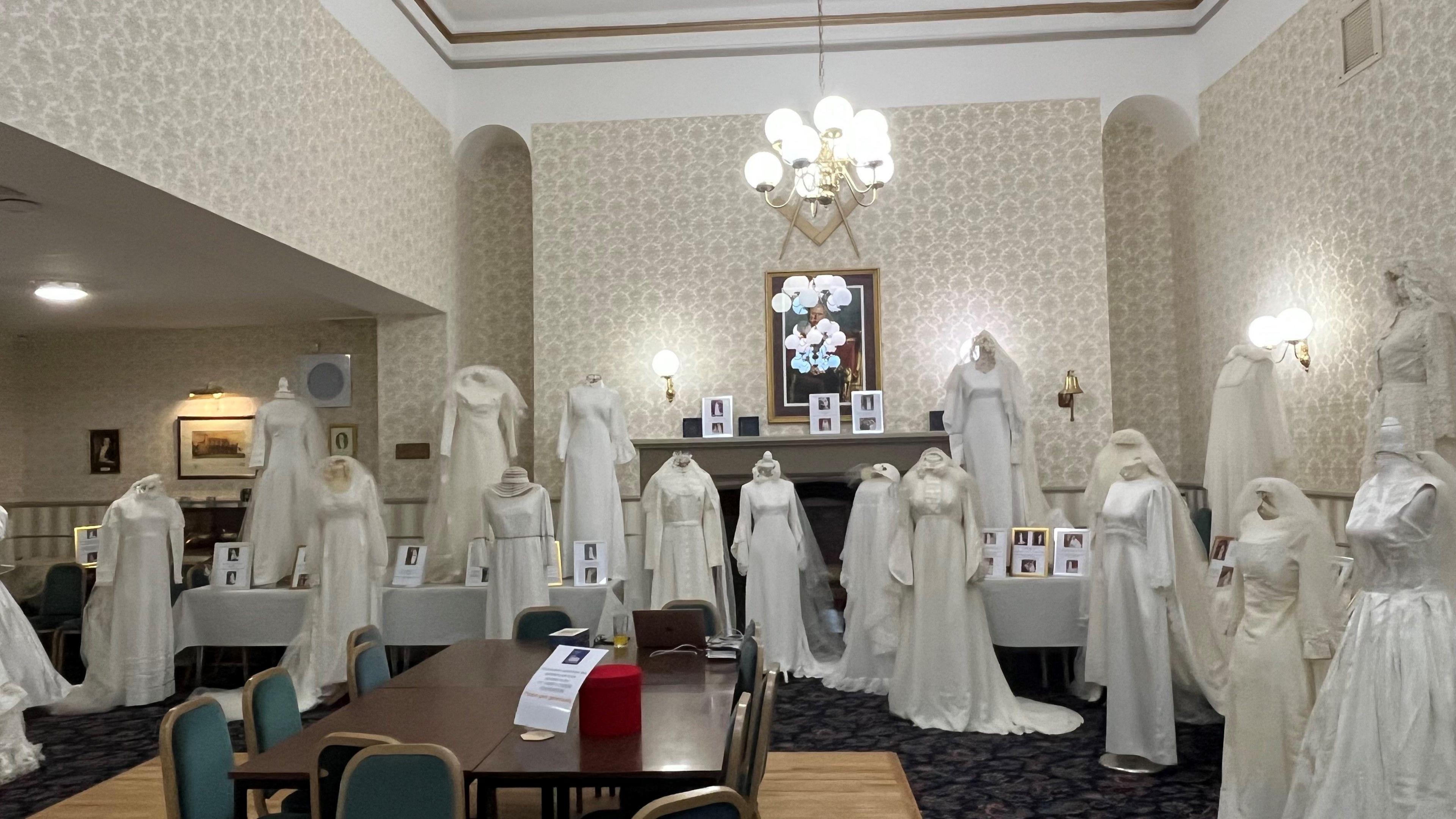About 16 wedding dresses are lining the edge of a spacious room inside Queen Street Masonic Temple in Sunderland. There are photos and a short text description next to each gown, telling the story of the bride who wore it.