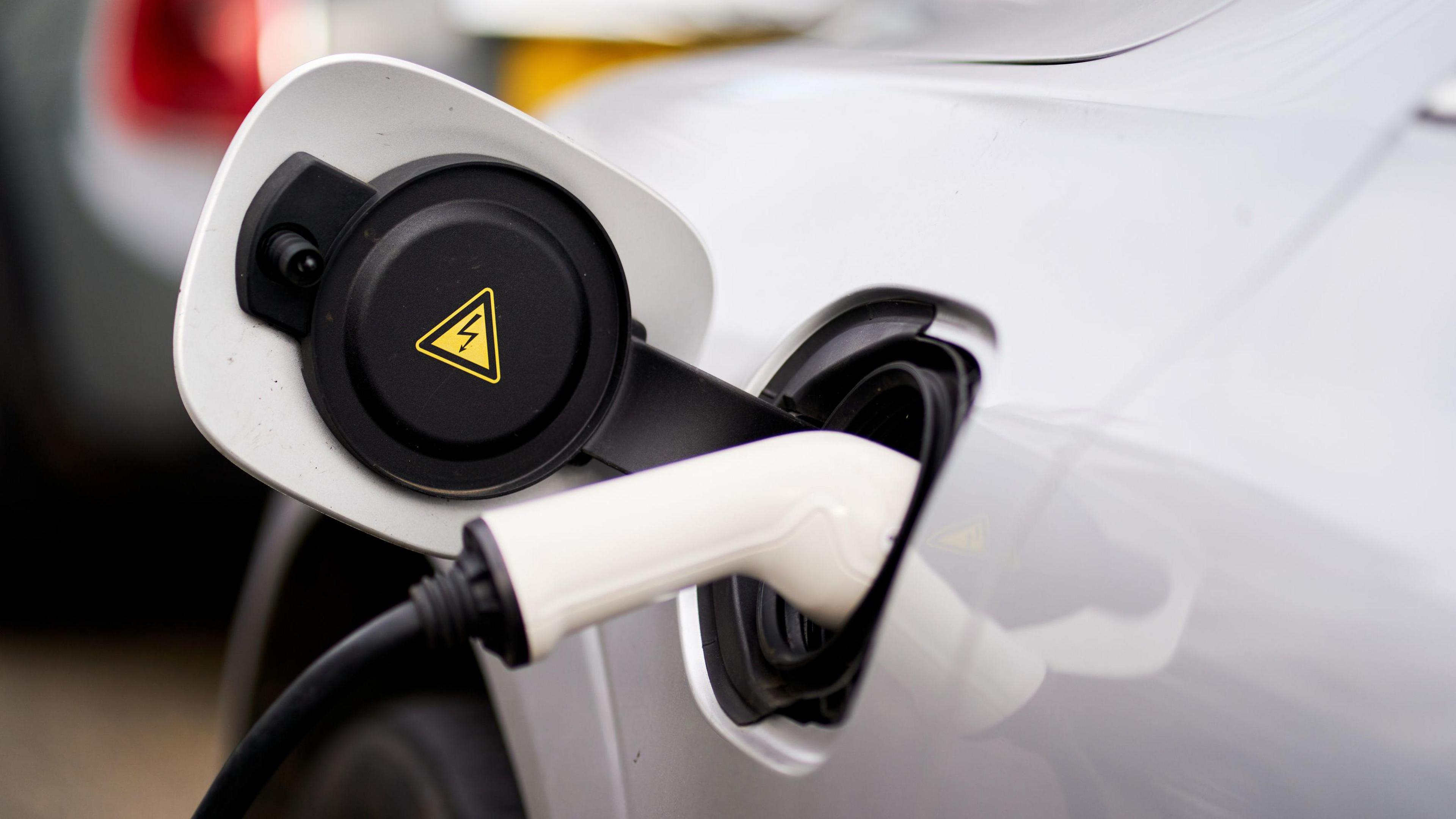 A white car being charged at an EV charging point.