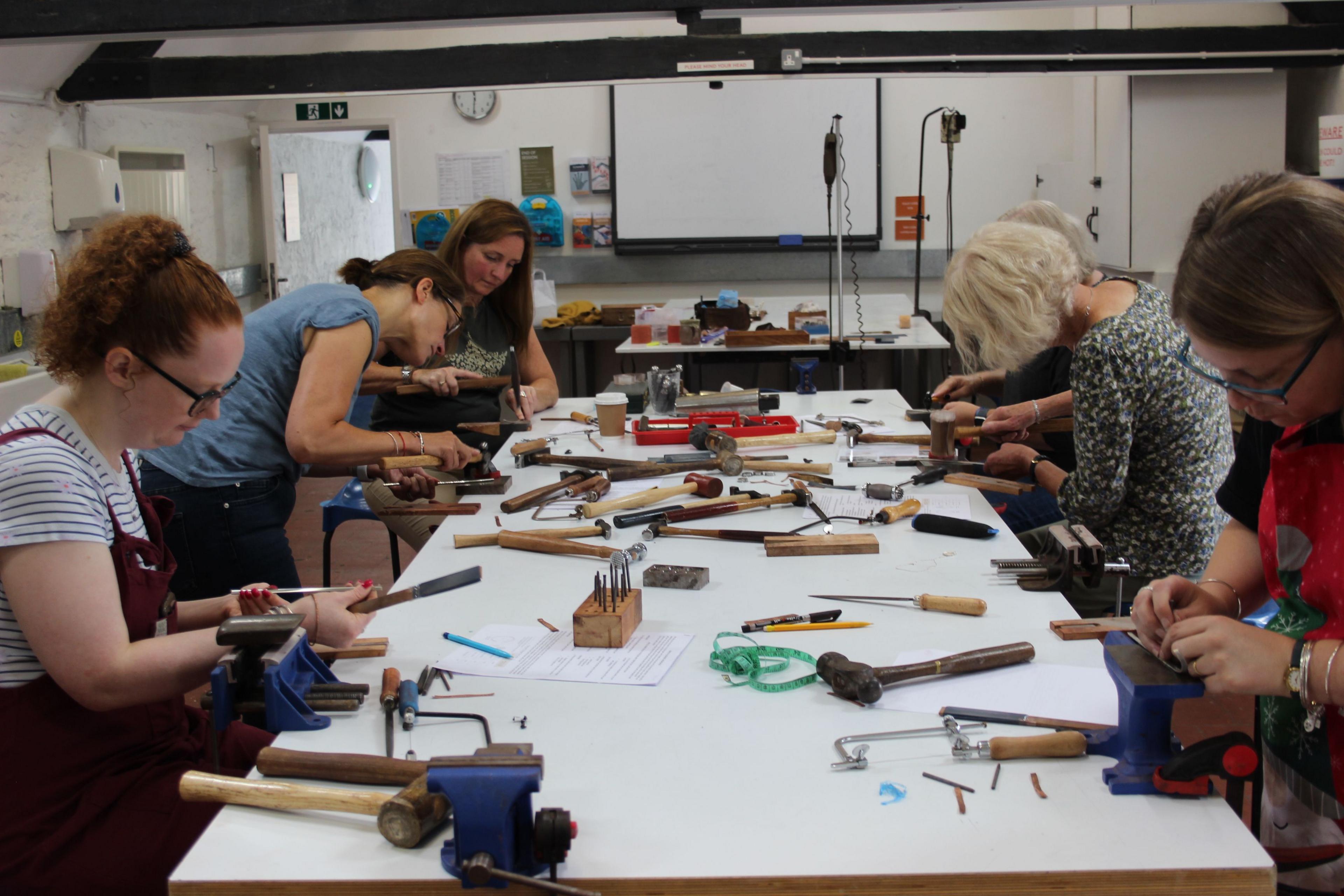 A group of women working on a large table at a jewellery making workshop