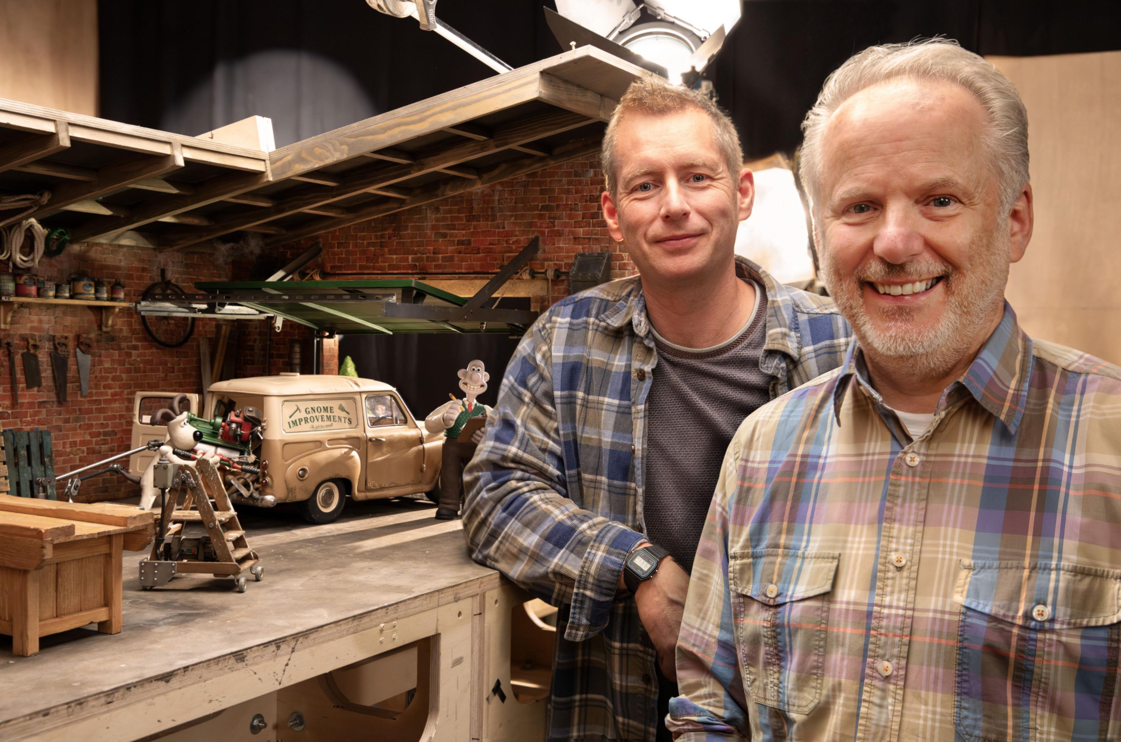 merlin crossingham and nick park in front of a model of wallace and gromit in a garage