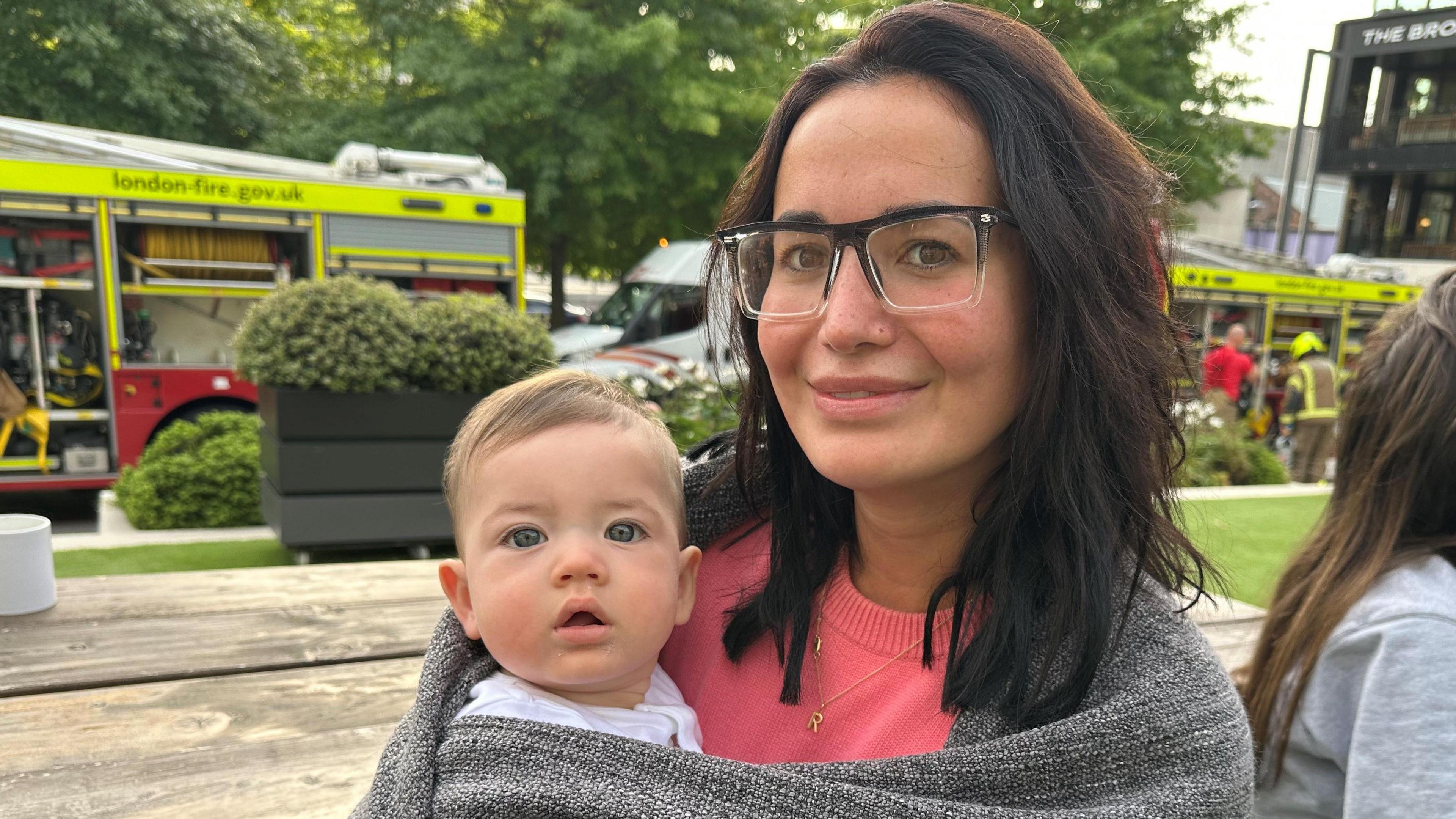 Isabela Brooker wrapped in a grey blanket holding her son. 