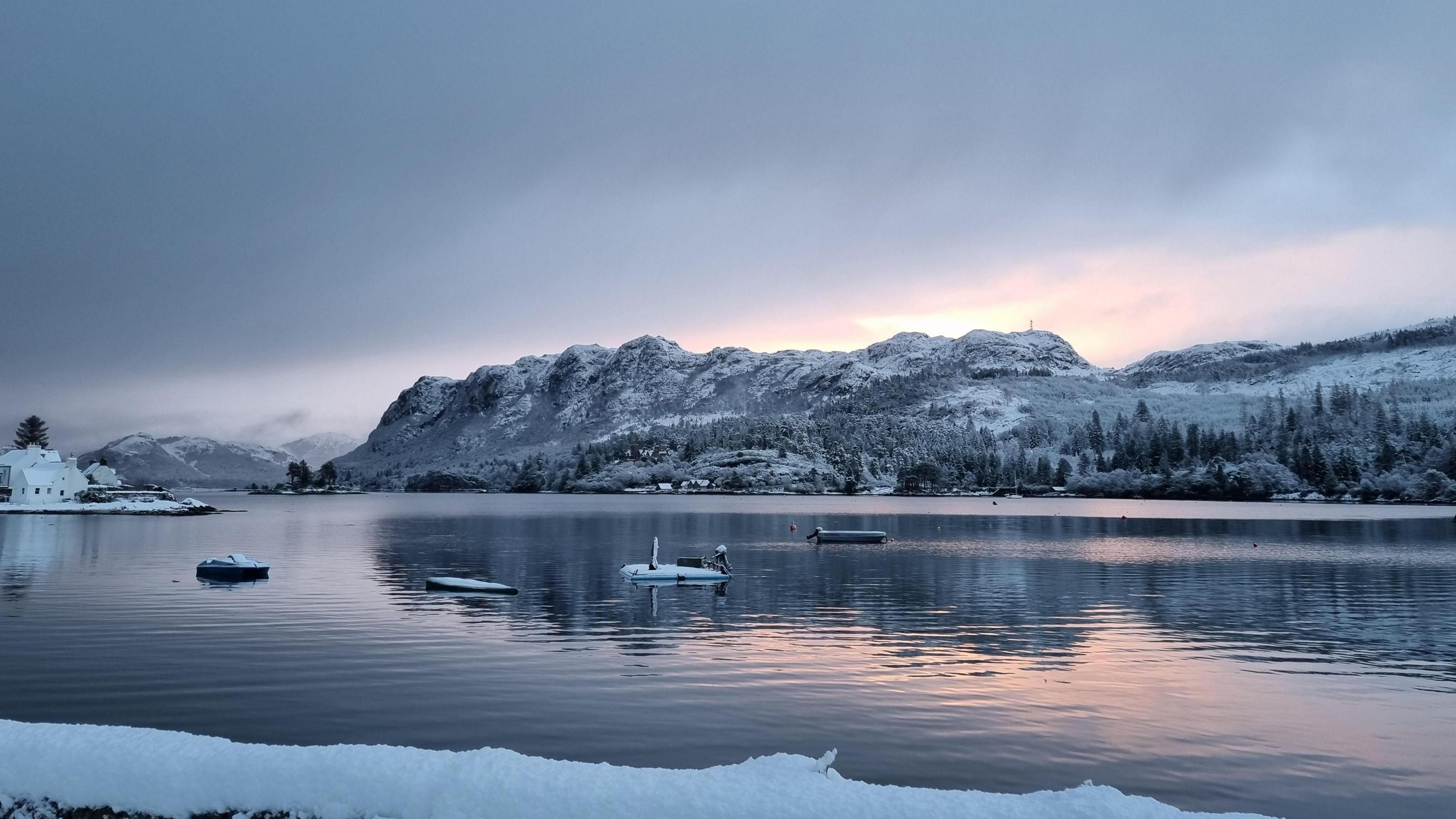 View across a loch to a snow-covered hilly landscape
