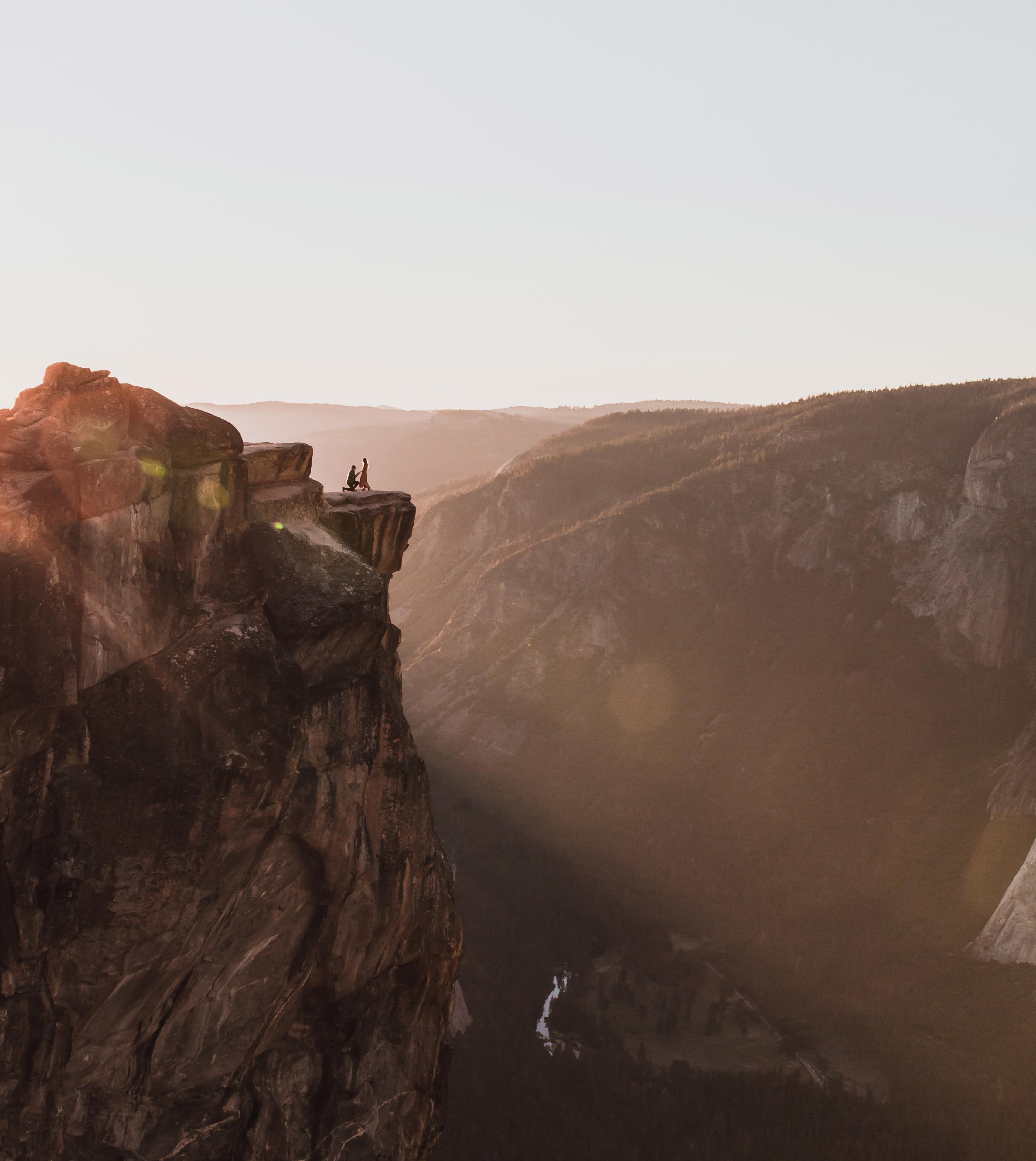 A dramatic shot shows a couple on a ledge at Taft Point in Yosemite