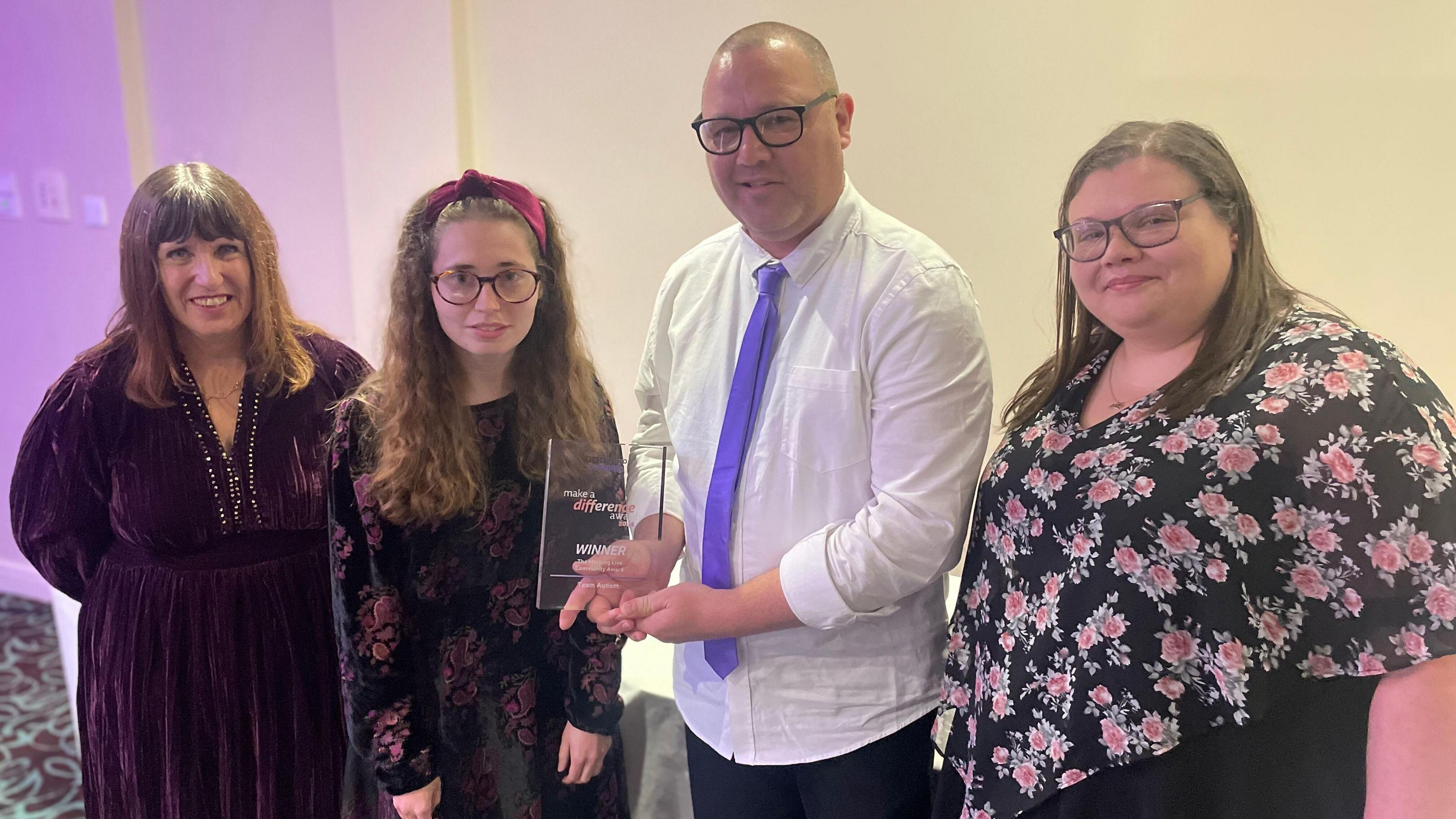 Four members of Penrith-based Team Autism standing together holding their community award.