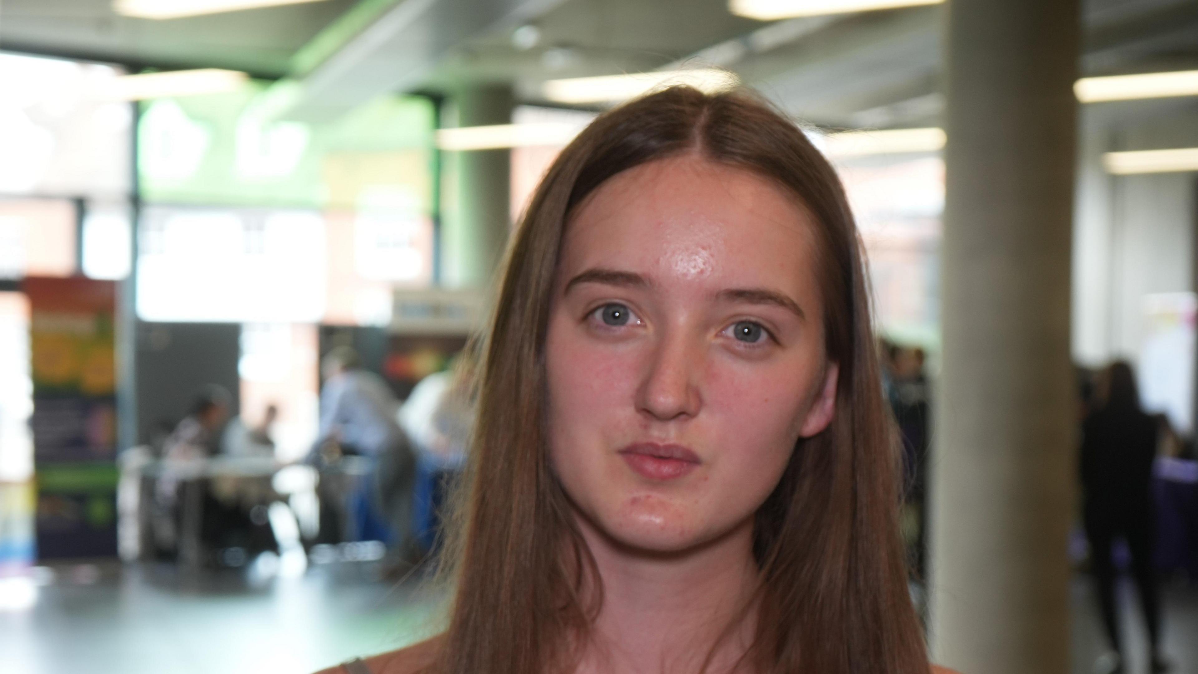 Teenager with shoulder length hair looks to camera