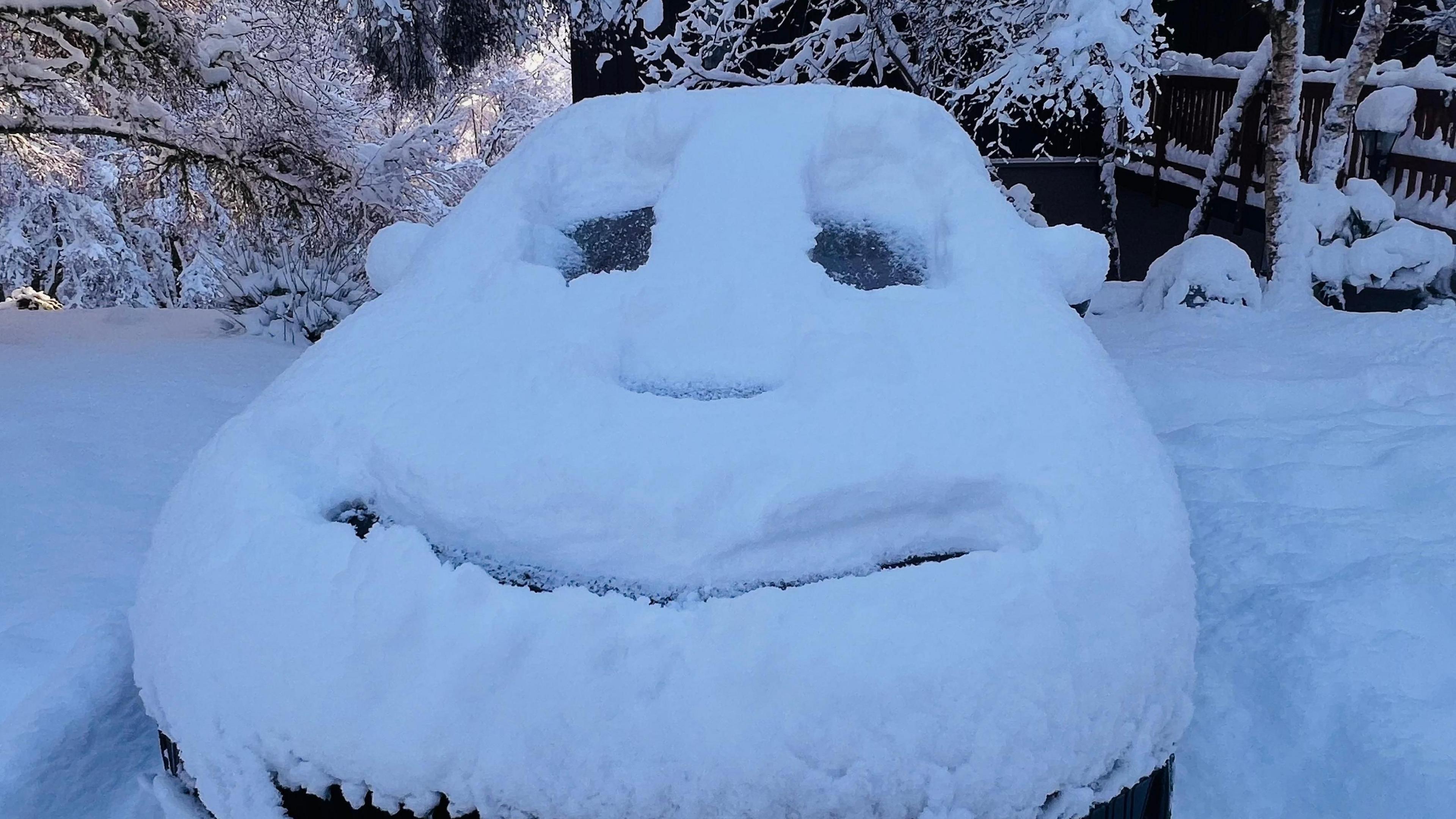 Smiley face carved into thick snow on a car
