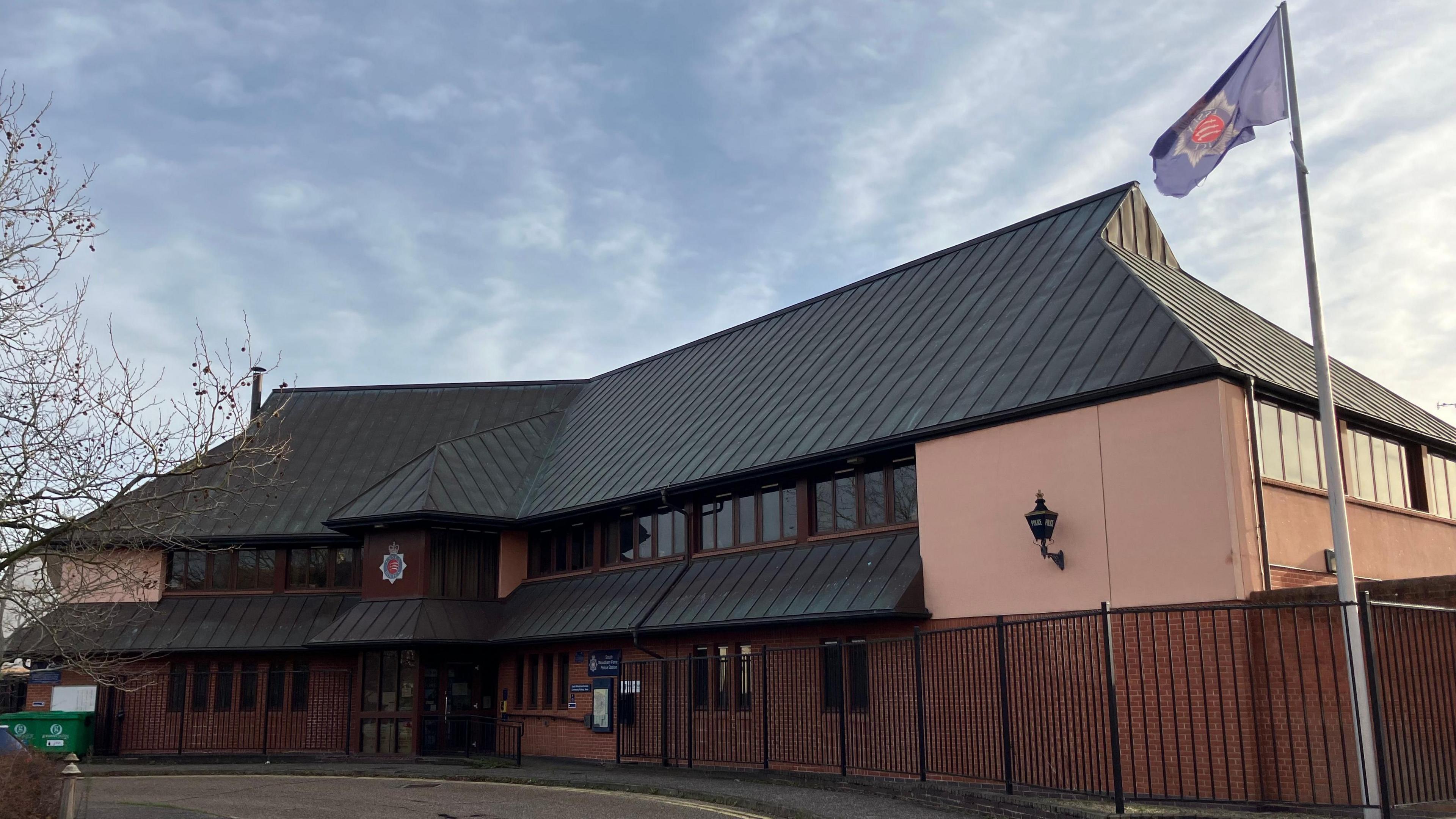A general view of South Woodham Ferrers police station. A two-storey building with bricks on the lower level and pinkish render on the upper. It has a black pitched roof.