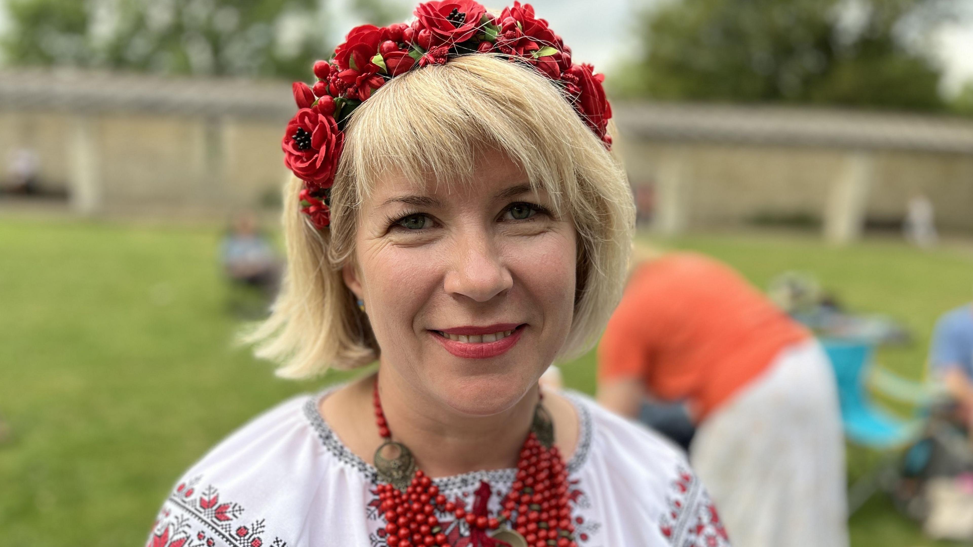 Uliana Khotynska with bobbed blonde hair wearing traditional clothes in red and white.