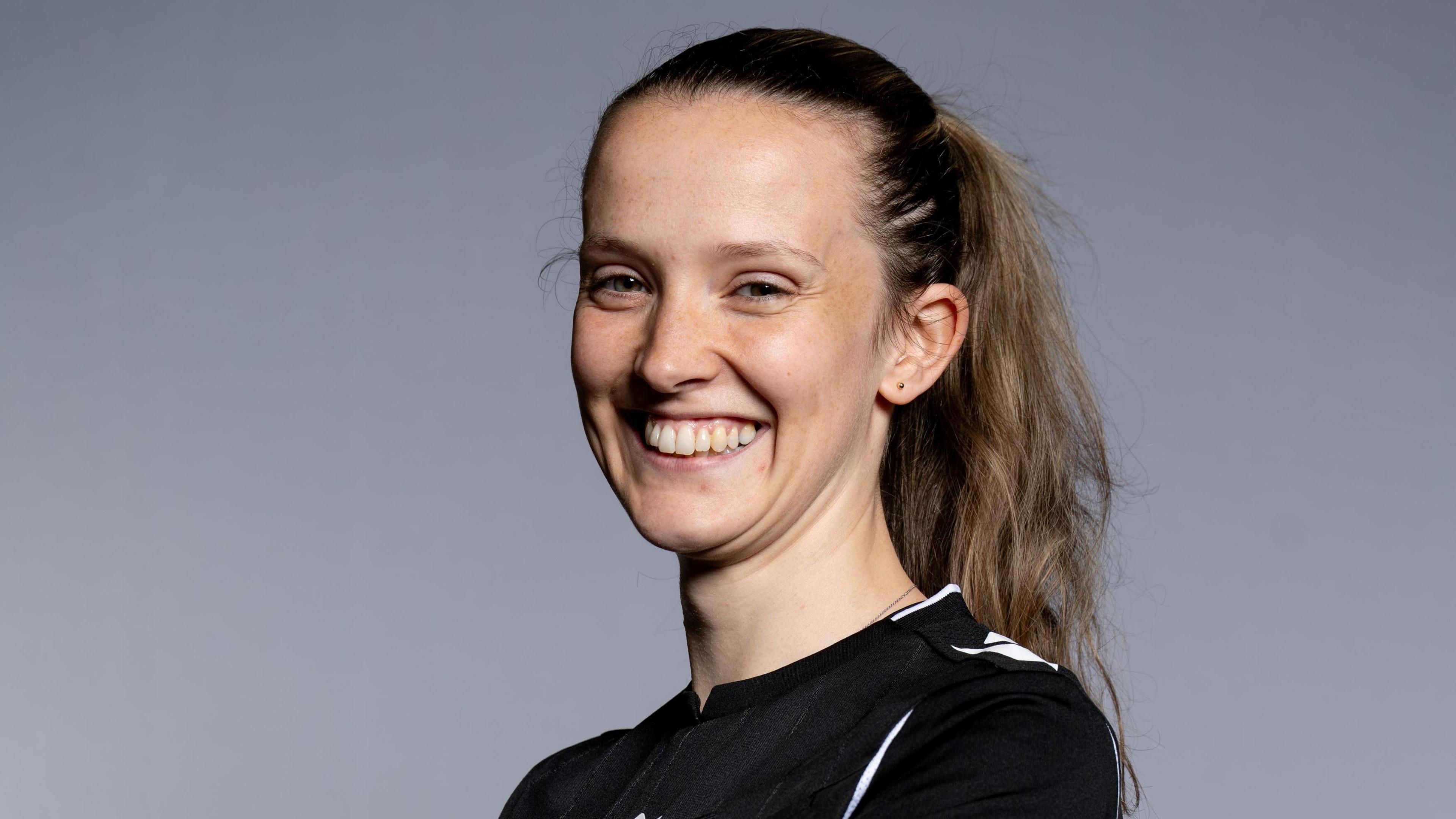 Headshot photo of Ceri Williams. She has mousy brown hair pulled back in a high ponytail and smiles showing her teeth.