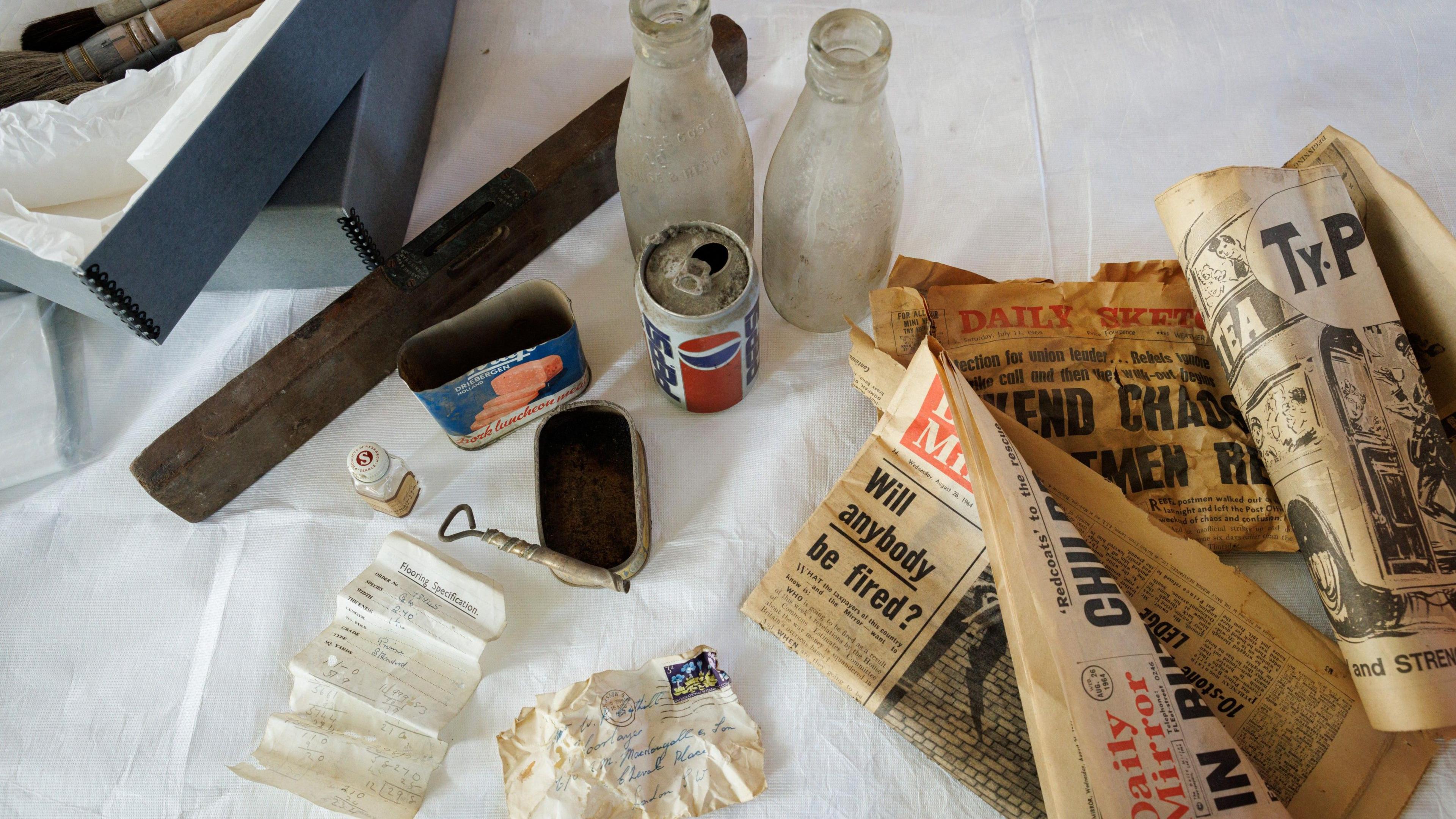 Some of the findings under the floor include Daily Mirror newspapers, a crinkled envelope, an open tine of sardines, an open can of Pepsi, flooring specifications and two glass bottles. 