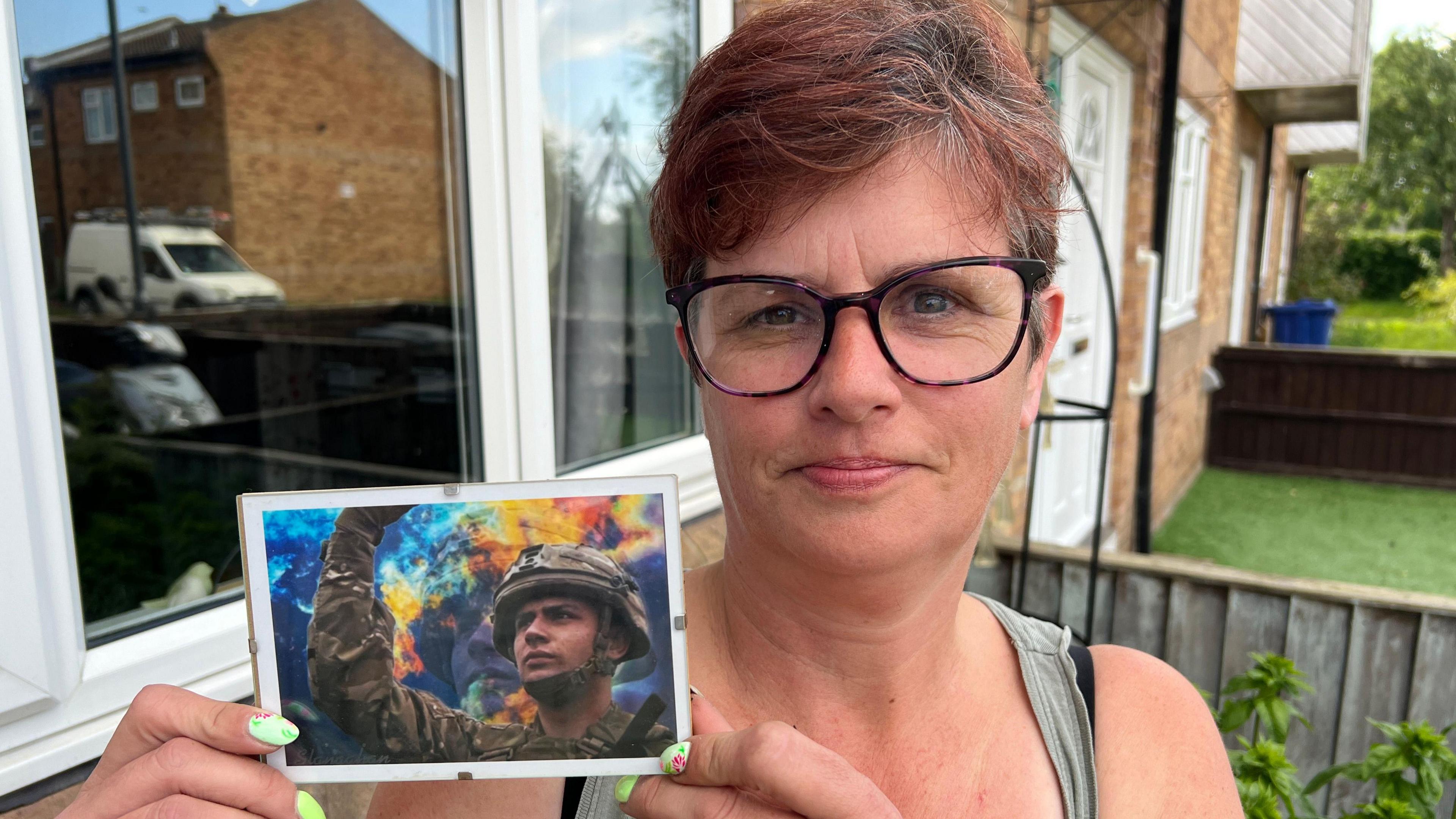 Janette is pictured in her garden holding a photograph of her son Bradley in militrary uniform