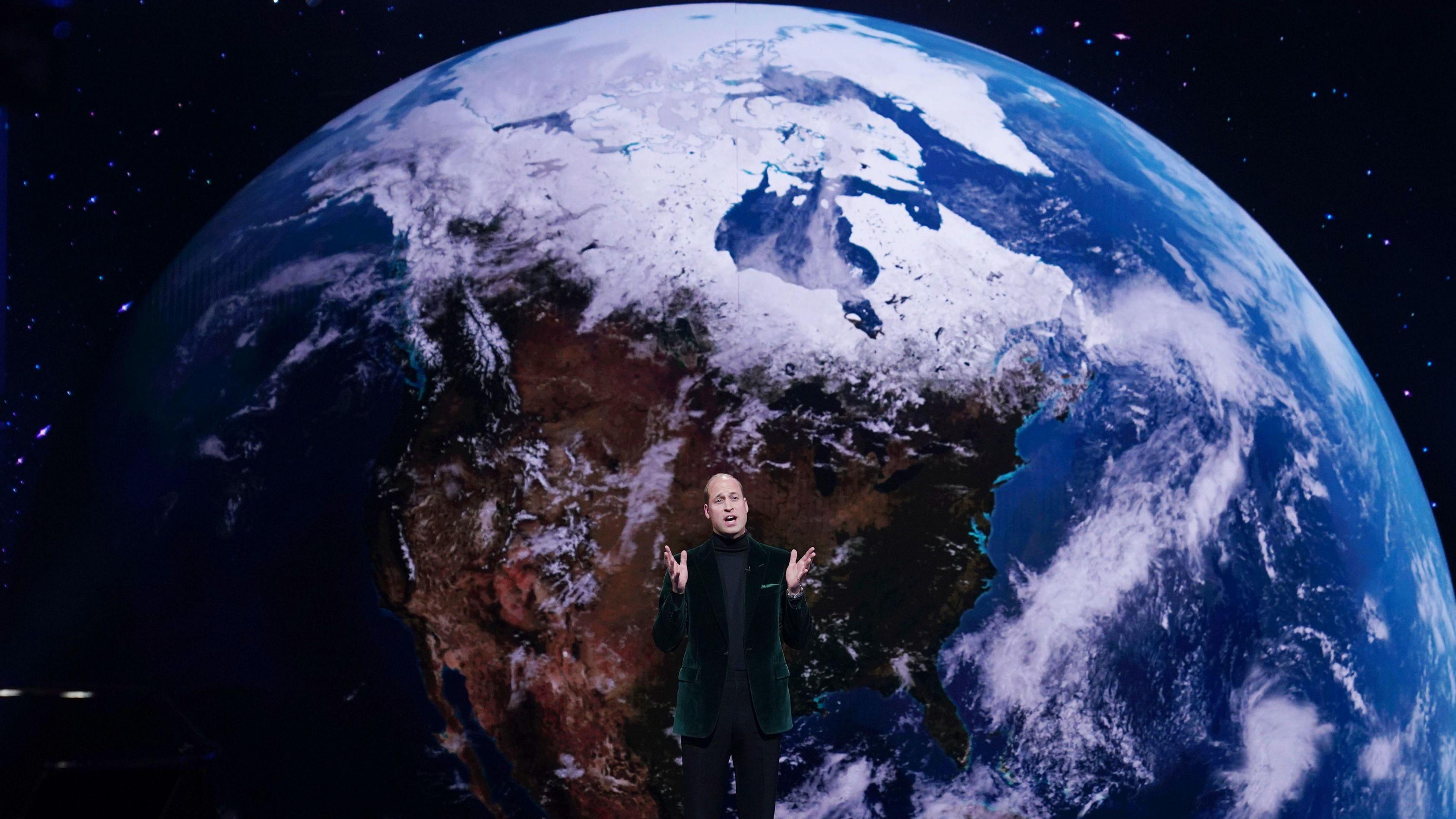 Prince William in front of a picture of the Earth