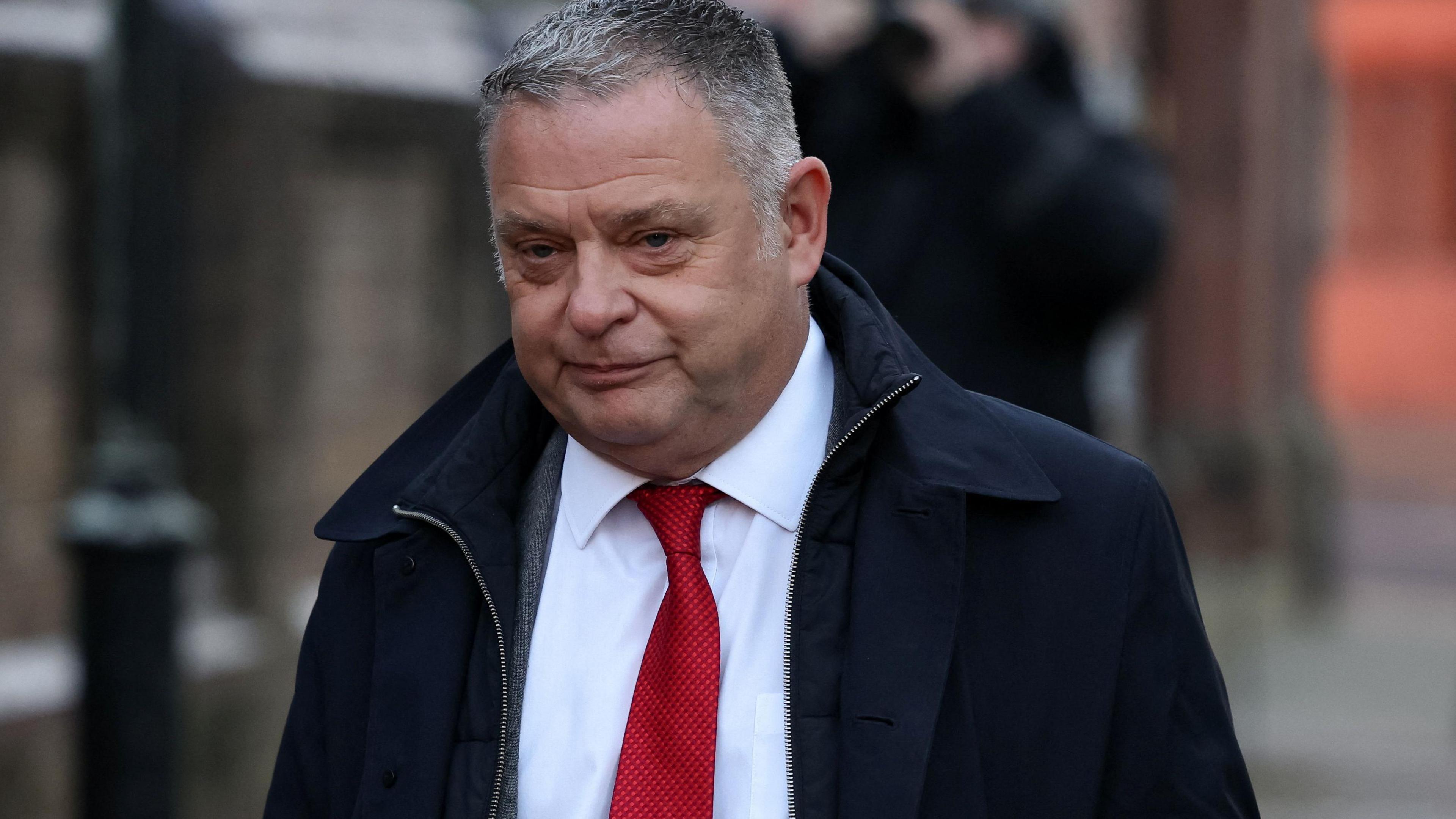 Mike Amesbury pictured arriving at court wearing a dark jacket over a white shirt and red tie