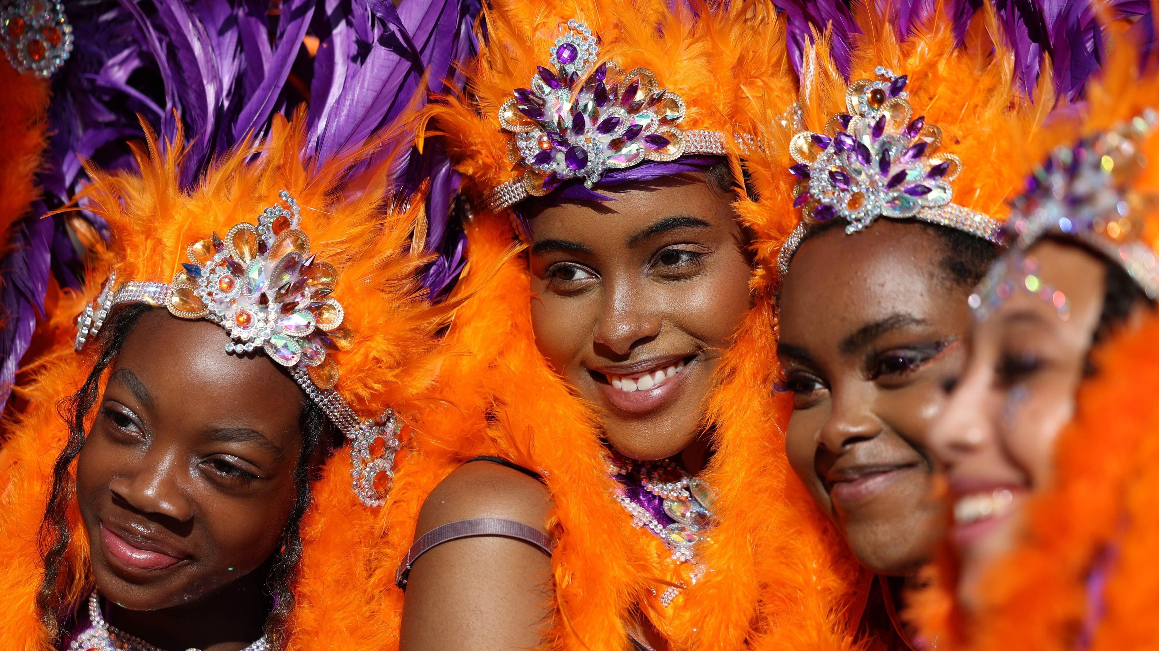 Three girls smiling in feathers and carnival jewels