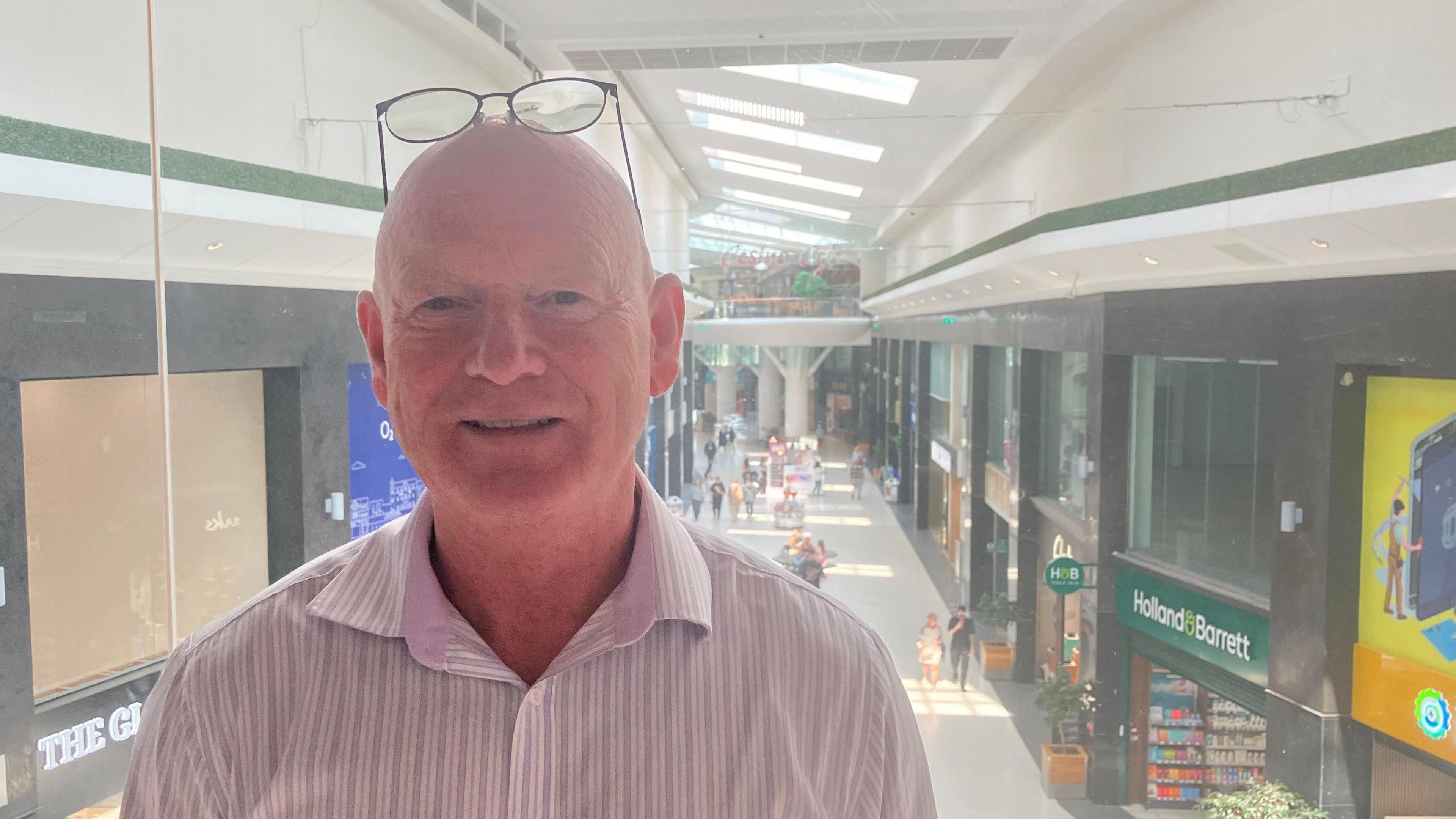 Photograph of Mike Matthews from the Grand Arcade shopping centre. he is pictured with the shopping mall behind him. 