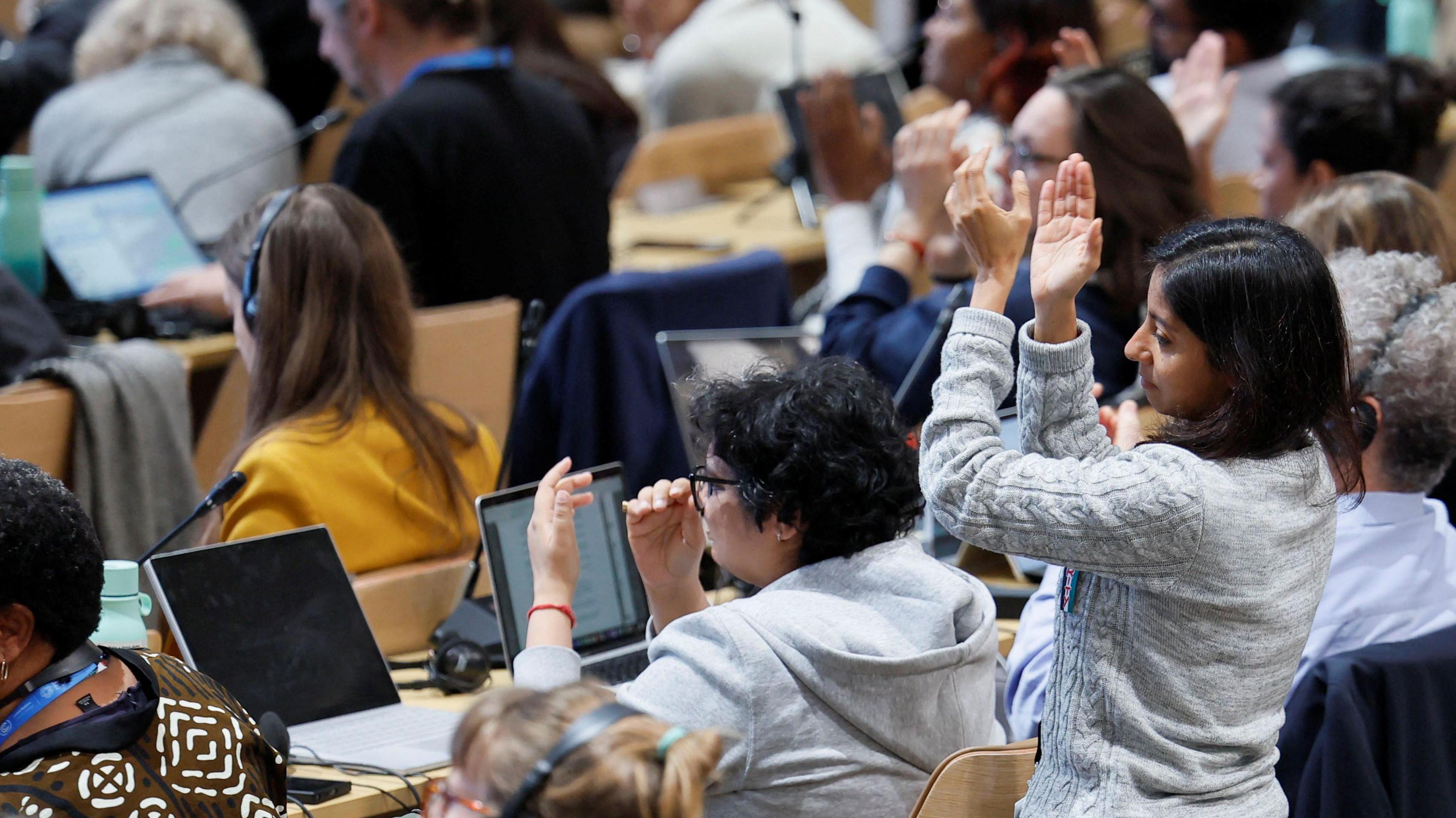 A group of people in a conference hall stand up and applaud