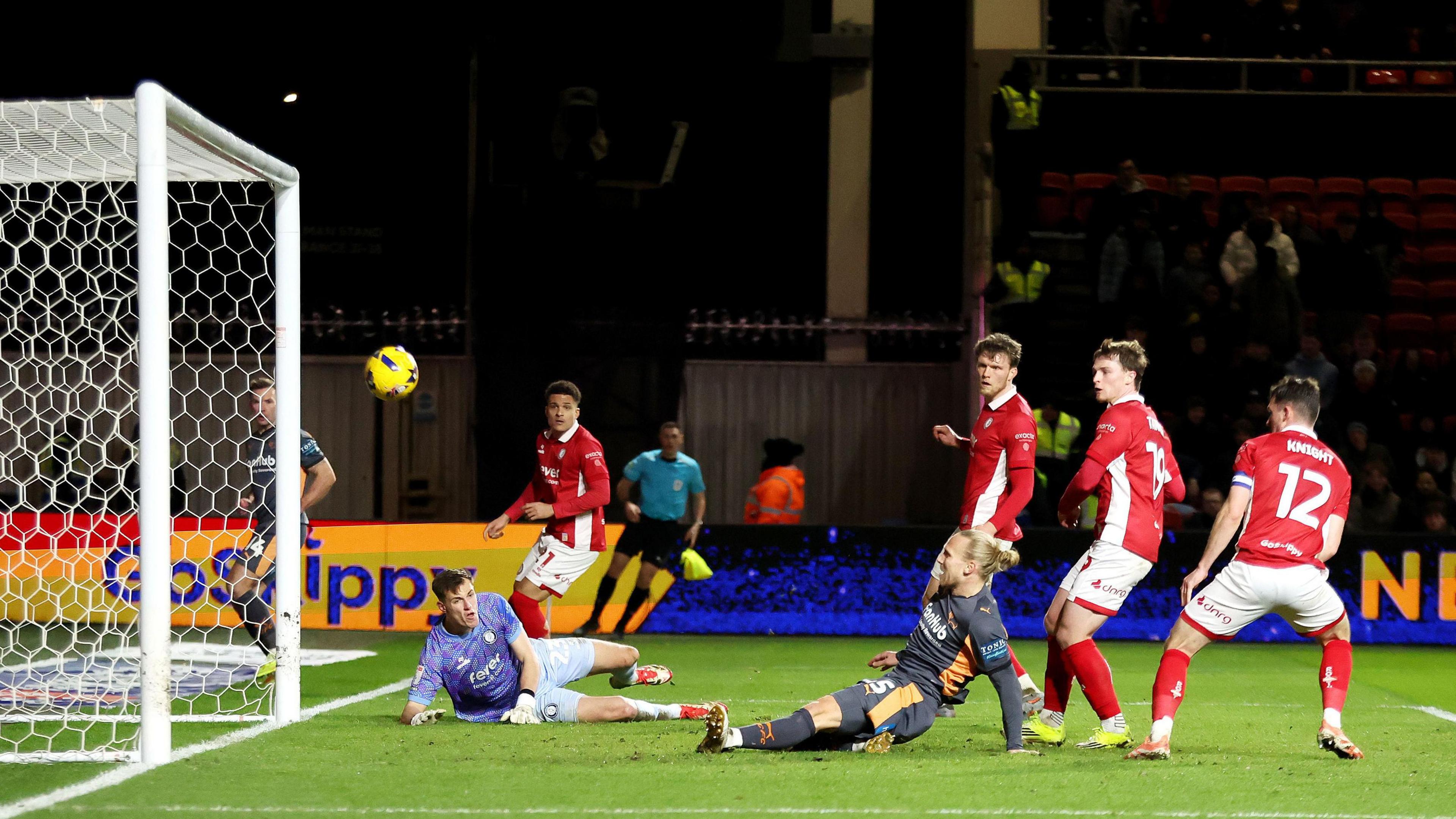 Lars-Jorgen Salvesen sits on the floor as he watches the ball fly towards the net, three Bristol City players stand in the box behind him, while Bristol City goalkeeper Radek Vitek lies down to his left 