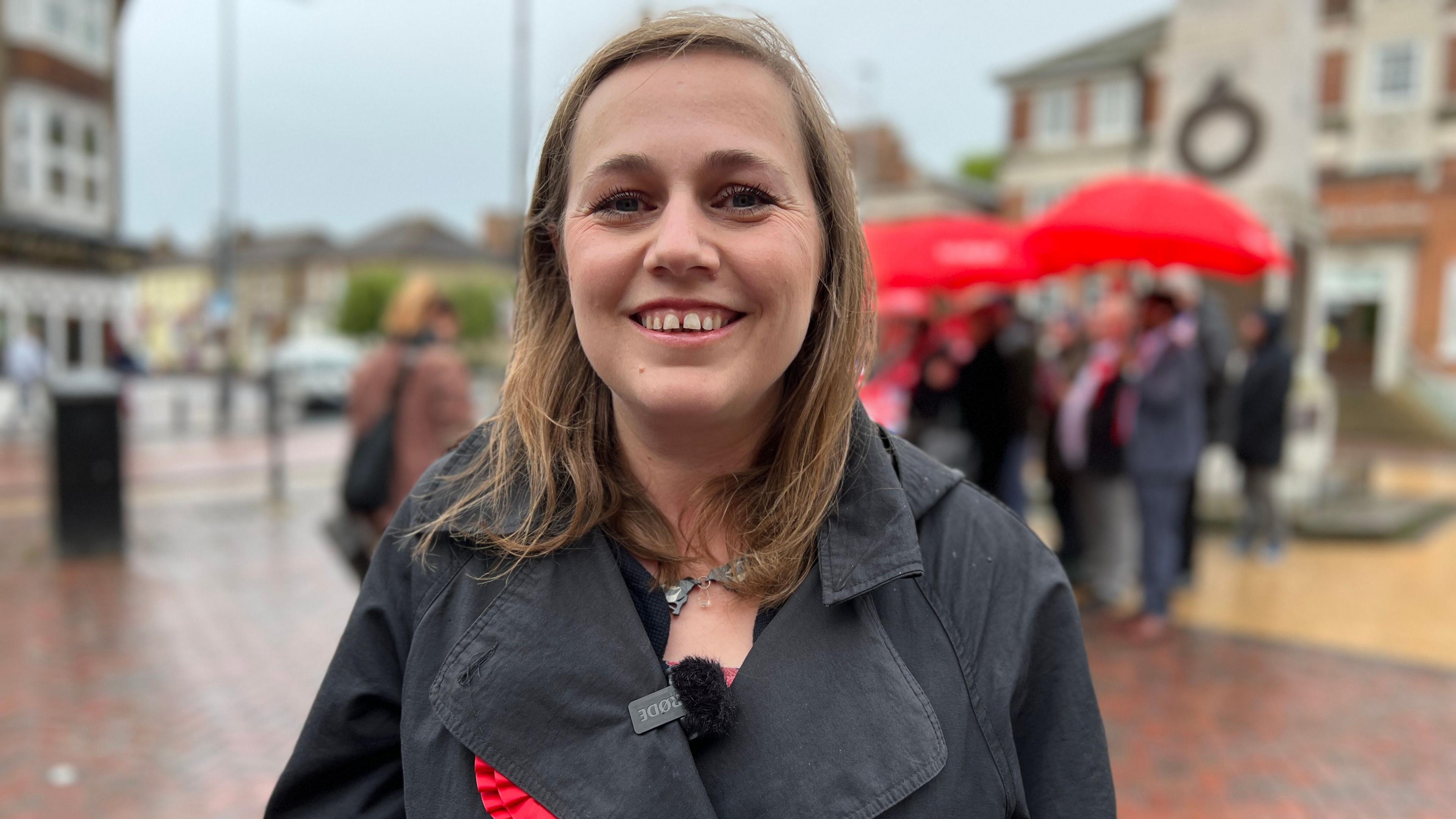 Jen Craft Thurrock MP standing in Grays High Street on a rainy day. She is smiling and looking at the camera.