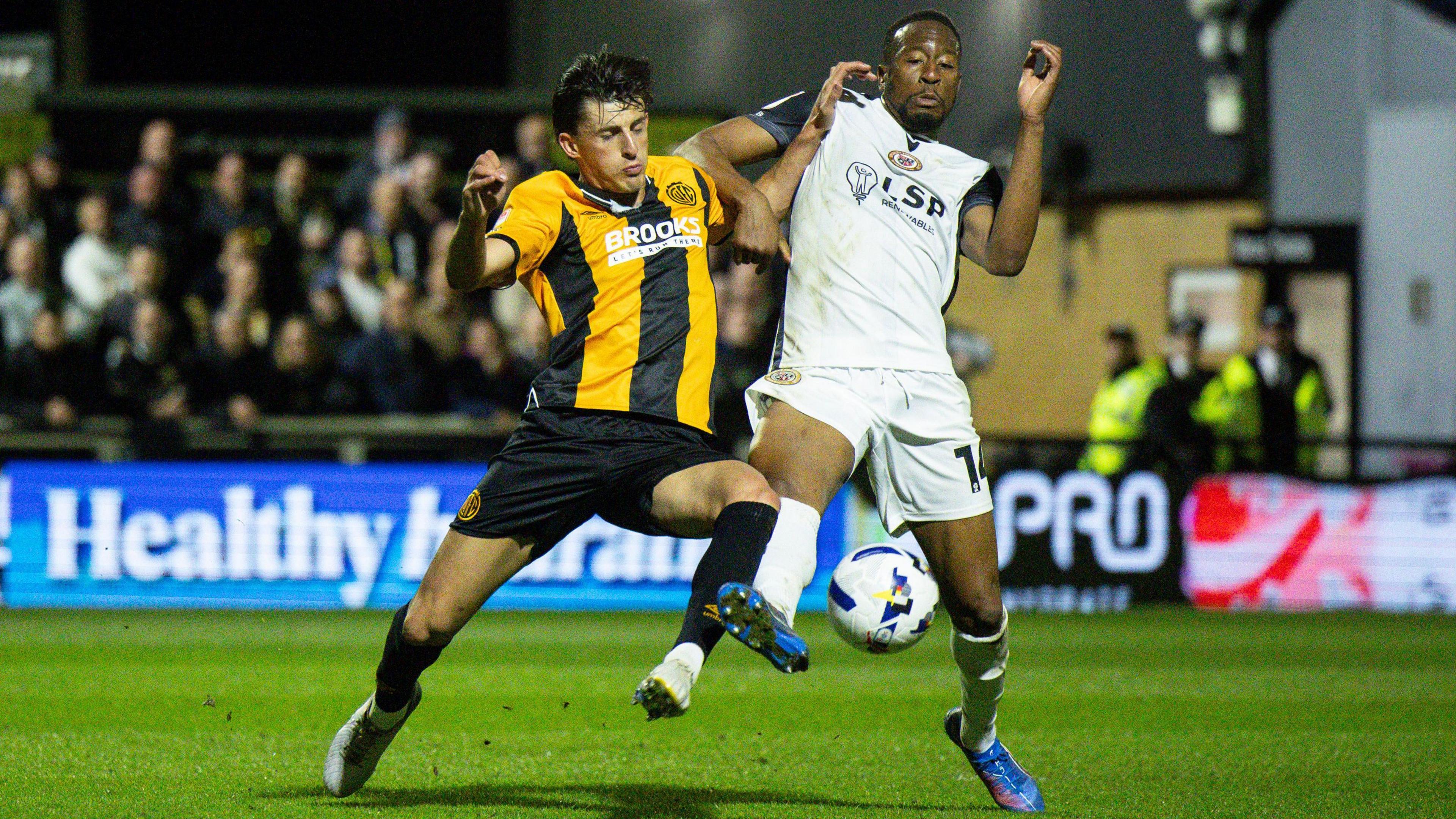 Kelland Watts of Cambridge United and Nicke Kabamba of Bromley tussle for the ball