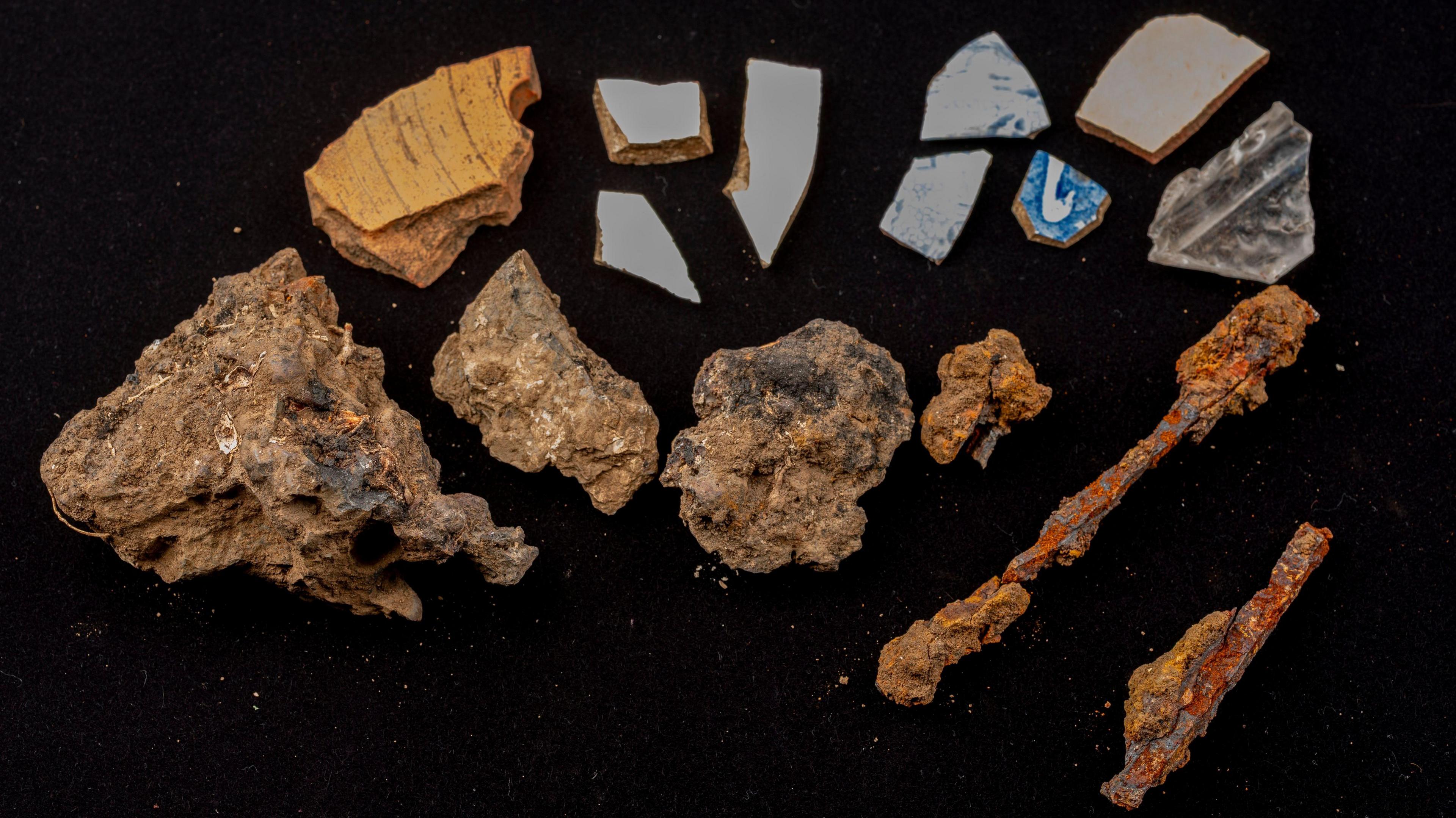 Pieces of blue pottery and tile are laid out on a black surface.