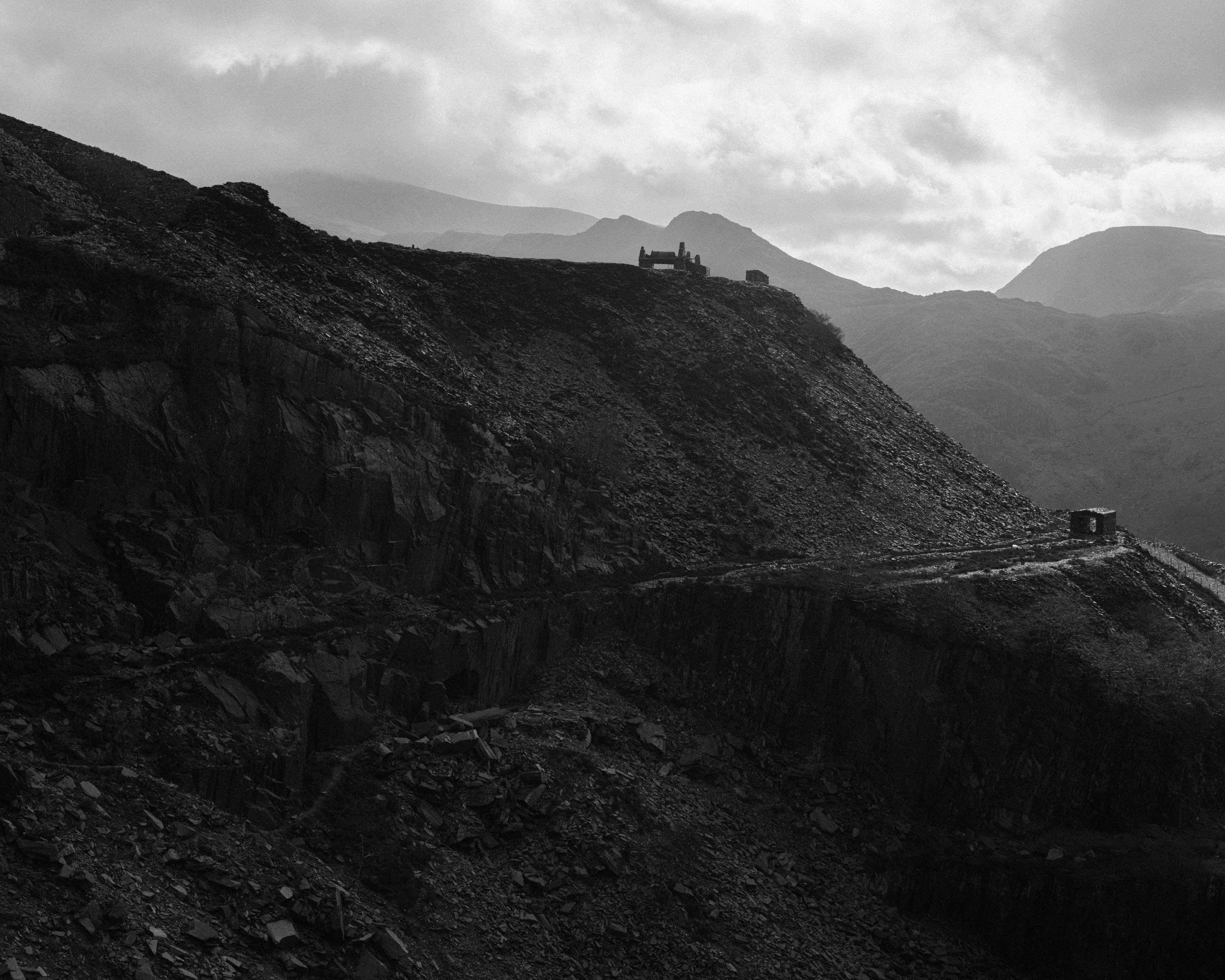 Kyle's black and white photograph of a mountain road running past a large slag heap of slate spoil 