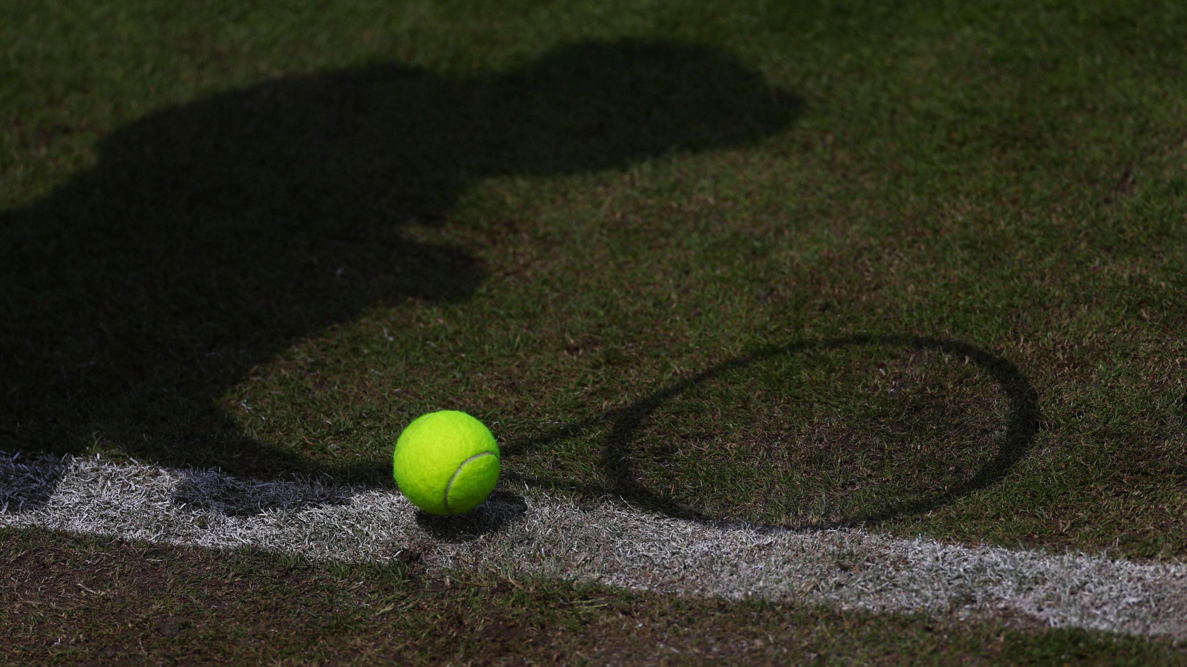 General view of a tennis ball pictured alongside a player's shadow 