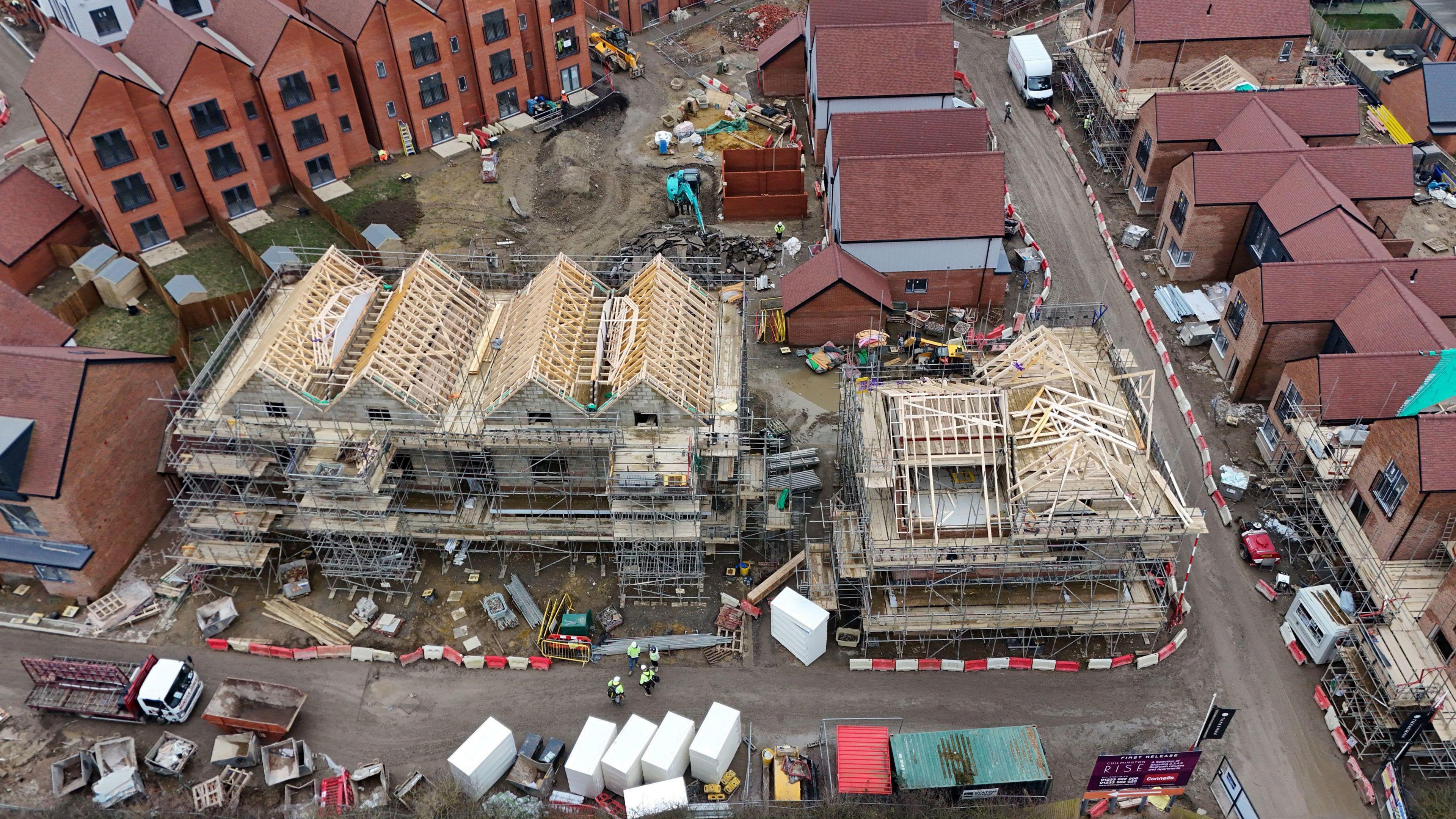 Aerial shot of new housing being built where you can see new homes with scaffolding and a timber frame on new build properties.