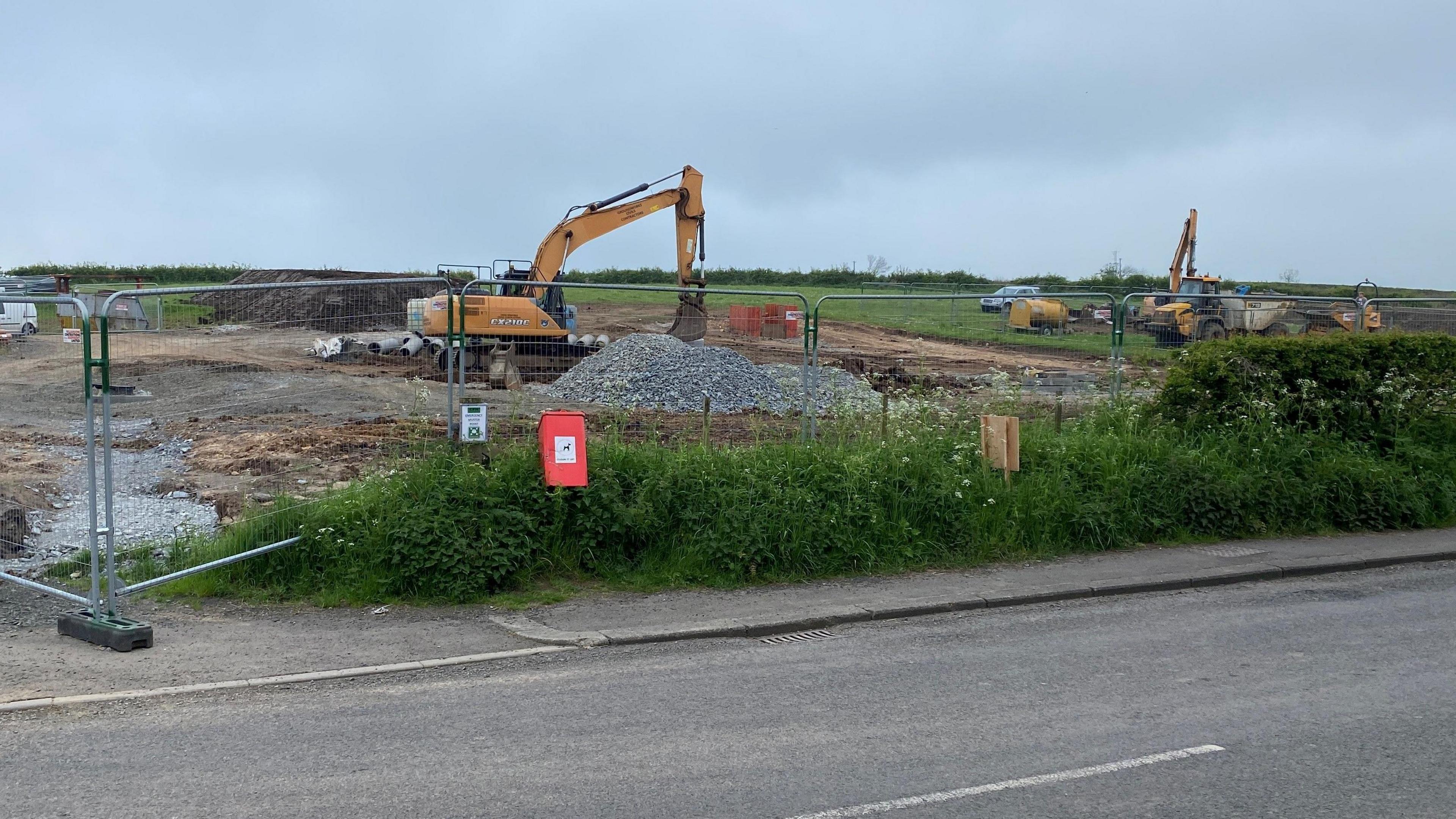 A digger at work in a field clearing the land